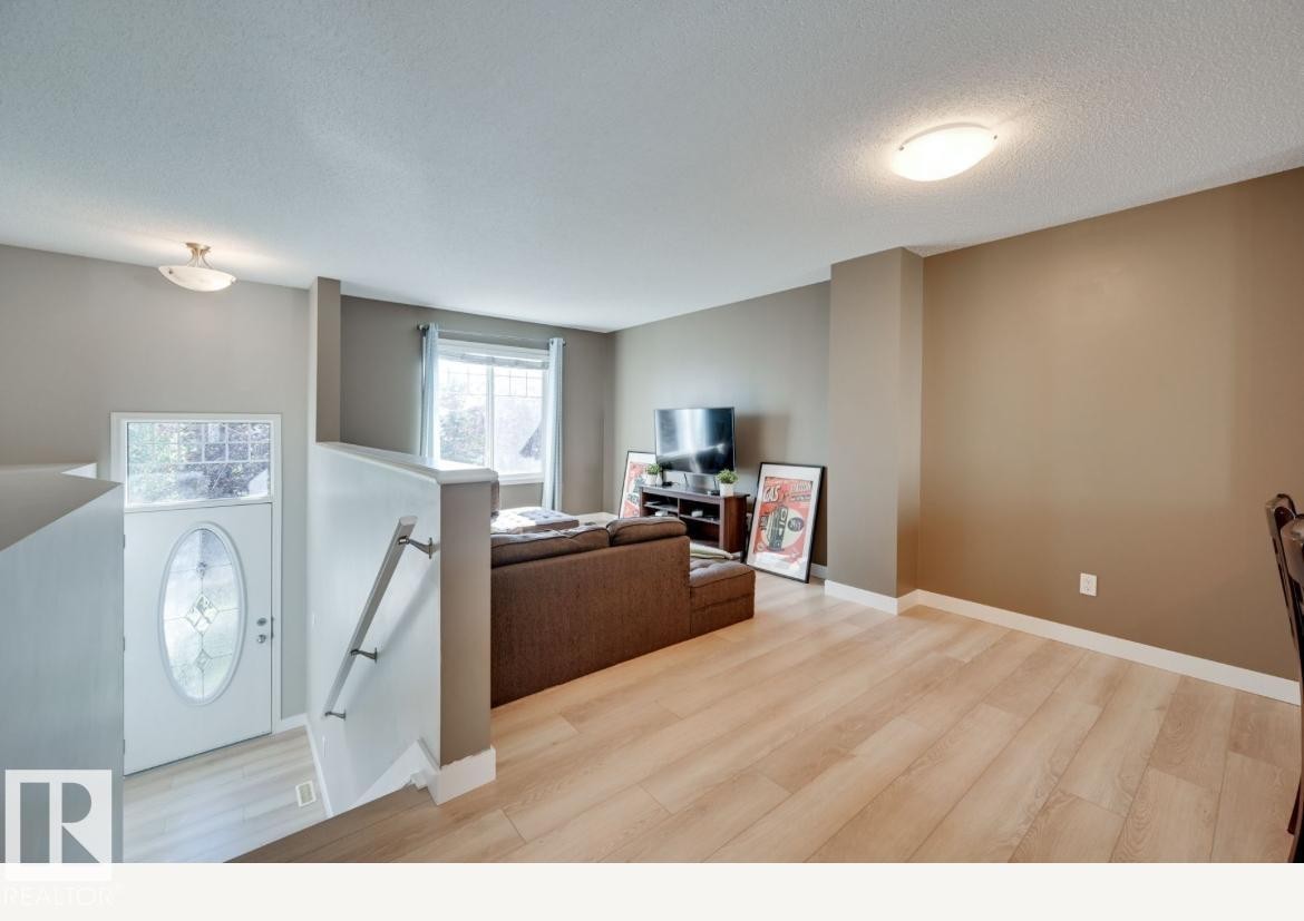 Open-concept living area featuring wood-finish flooring, neutral wall tones, and recessed lighting - #16 460 Hemingway Rd Nw, Edmonton, AB - Indoor