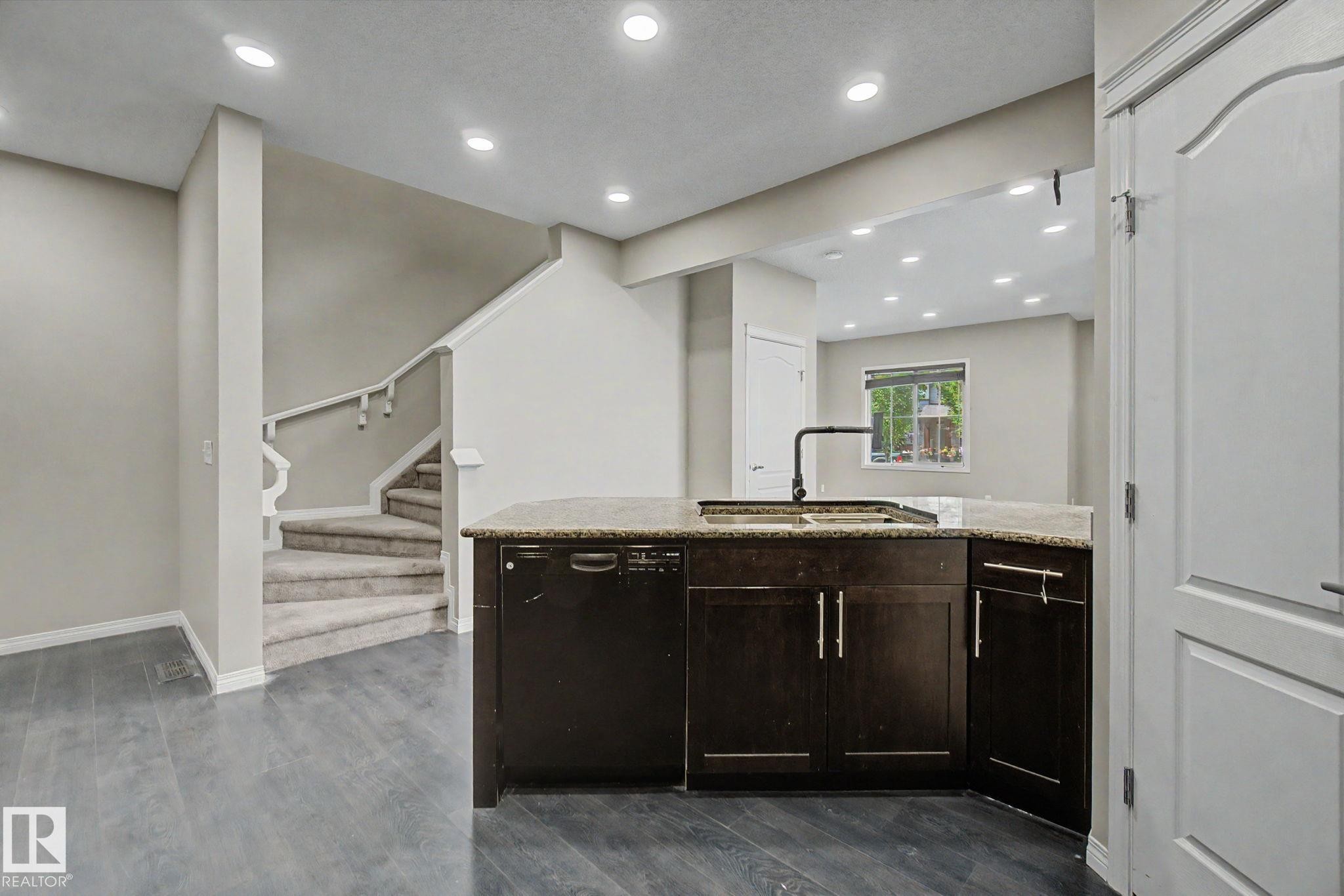 Kitchen island with dark wood cabinetry, granite countertop, and integrated sink - 315 Watt Boulevard Sw, Edmonton, AB - Indoor
