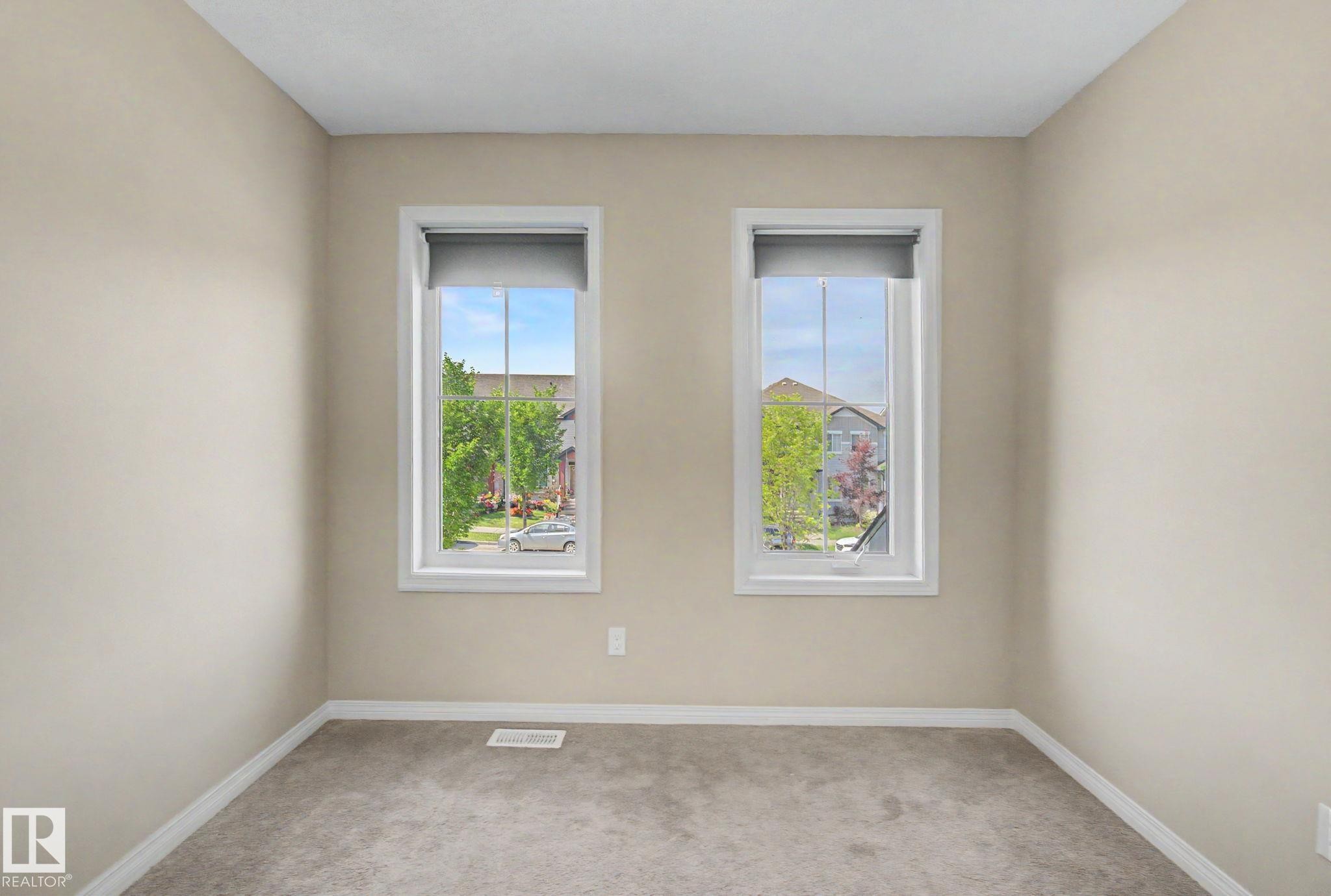 Room featuring two large windows with roller shades, neutral tone walls, and gray carpet - 315 Watt Boulevard Sw, Edmonton, AB - Indoor Photo Showing Other Room