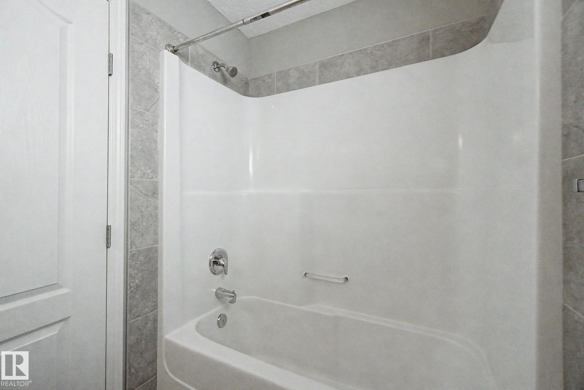 White bathtub and shower combination unit featuring a chrome showerhead and faucet - 315 Watt Boulevard Sw, Edmonton, AB - Indoor Photo Showing Bathroom