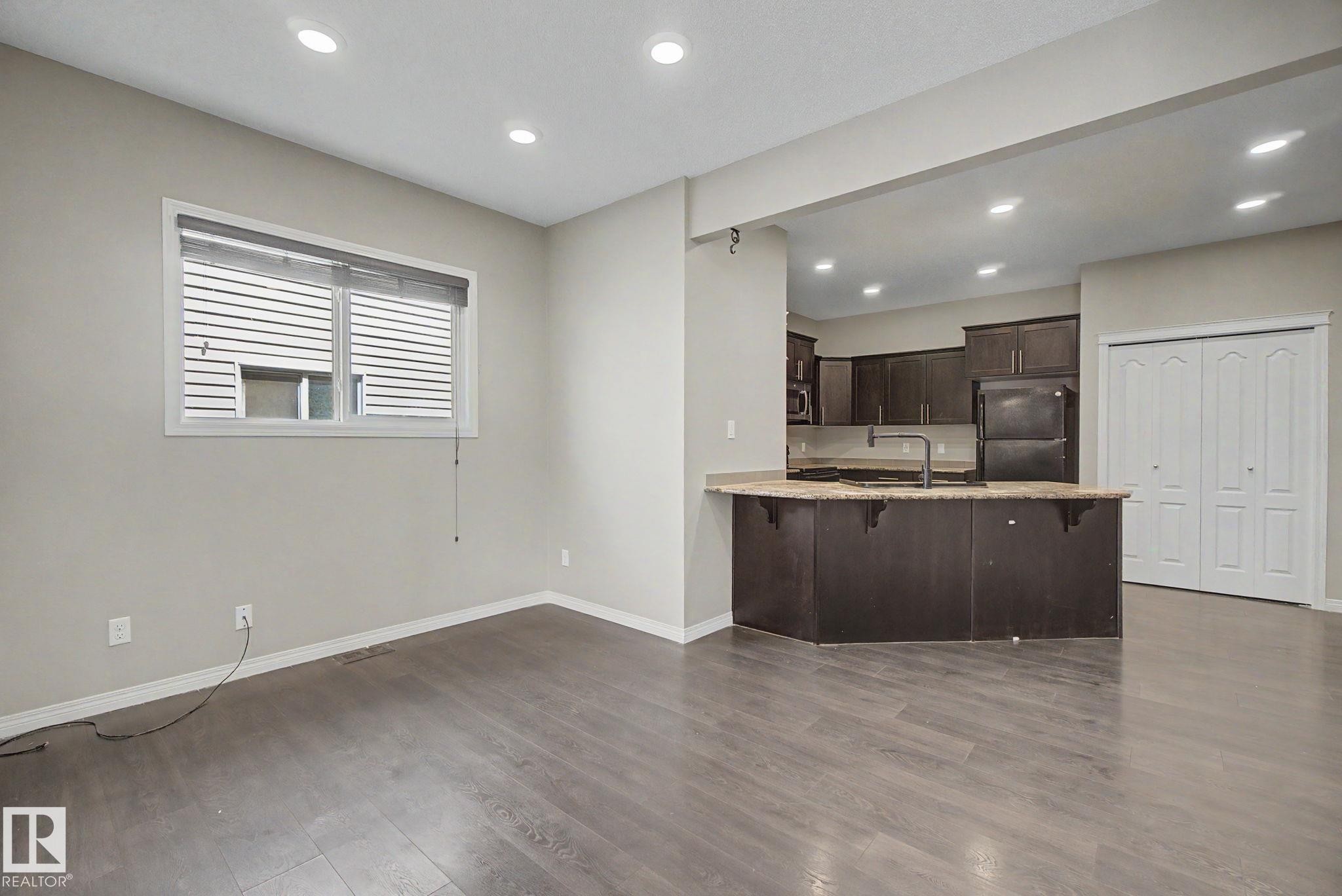 Open-concept living space featuring wood-finish flooring, recessed lighting, and a window with blinds - 315 Watt Boulevard Sw, Edmonton, AB - Indoor Photo Showing Kitchen