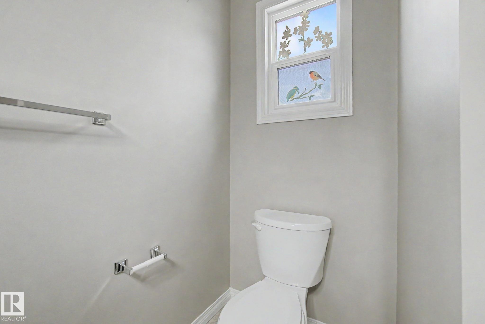 White toilet with a decorative window featuring a bird motif - 315 Watt Boulevard Sw, Edmonton, AB - Indoor Photo Showing Bathroom