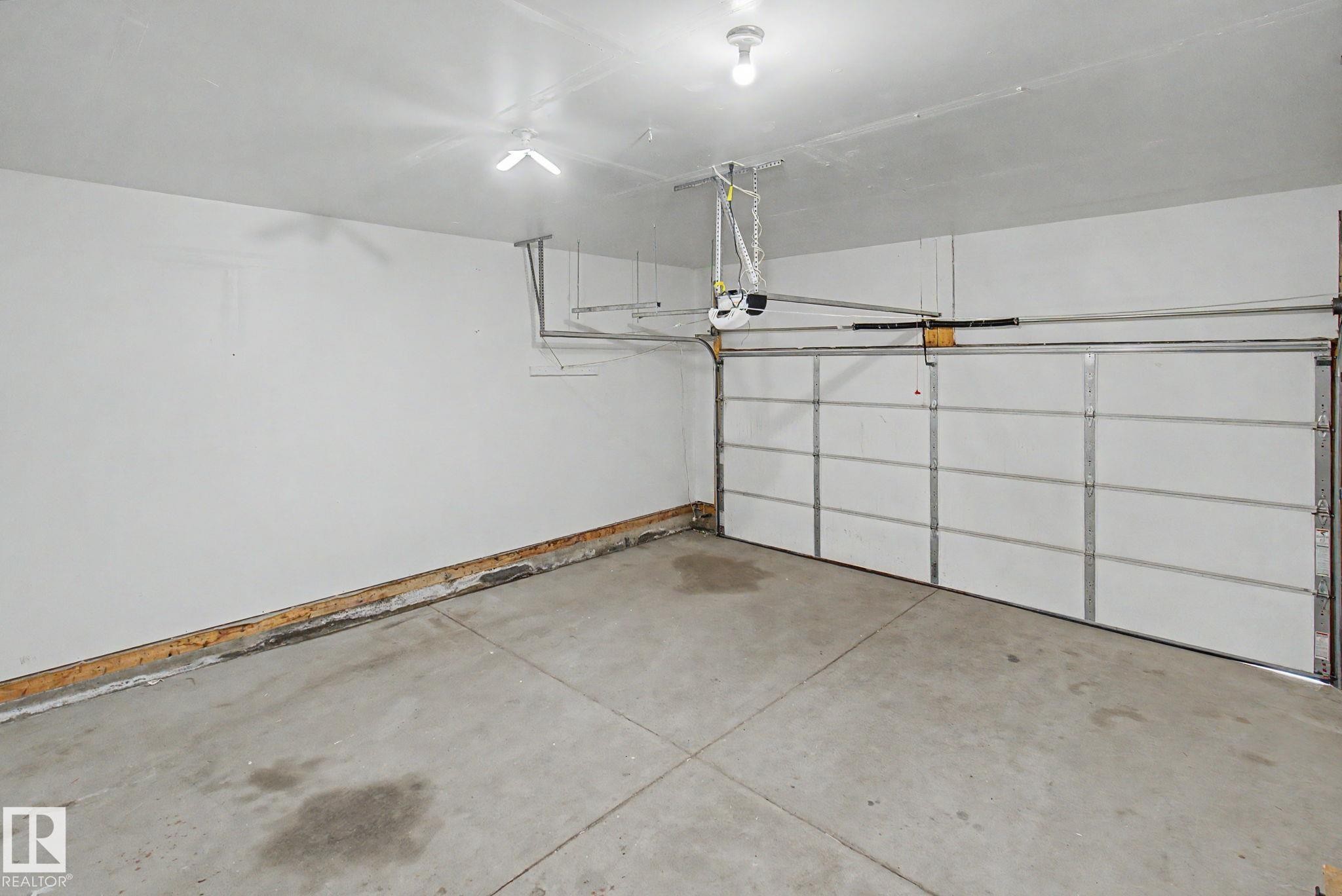 Spacious garage with concrete flooring, white walls, and an automatic garage door opener - 315 Watt Boulevard Sw, Edmonton, AB - Indoor Photo Showing Garage