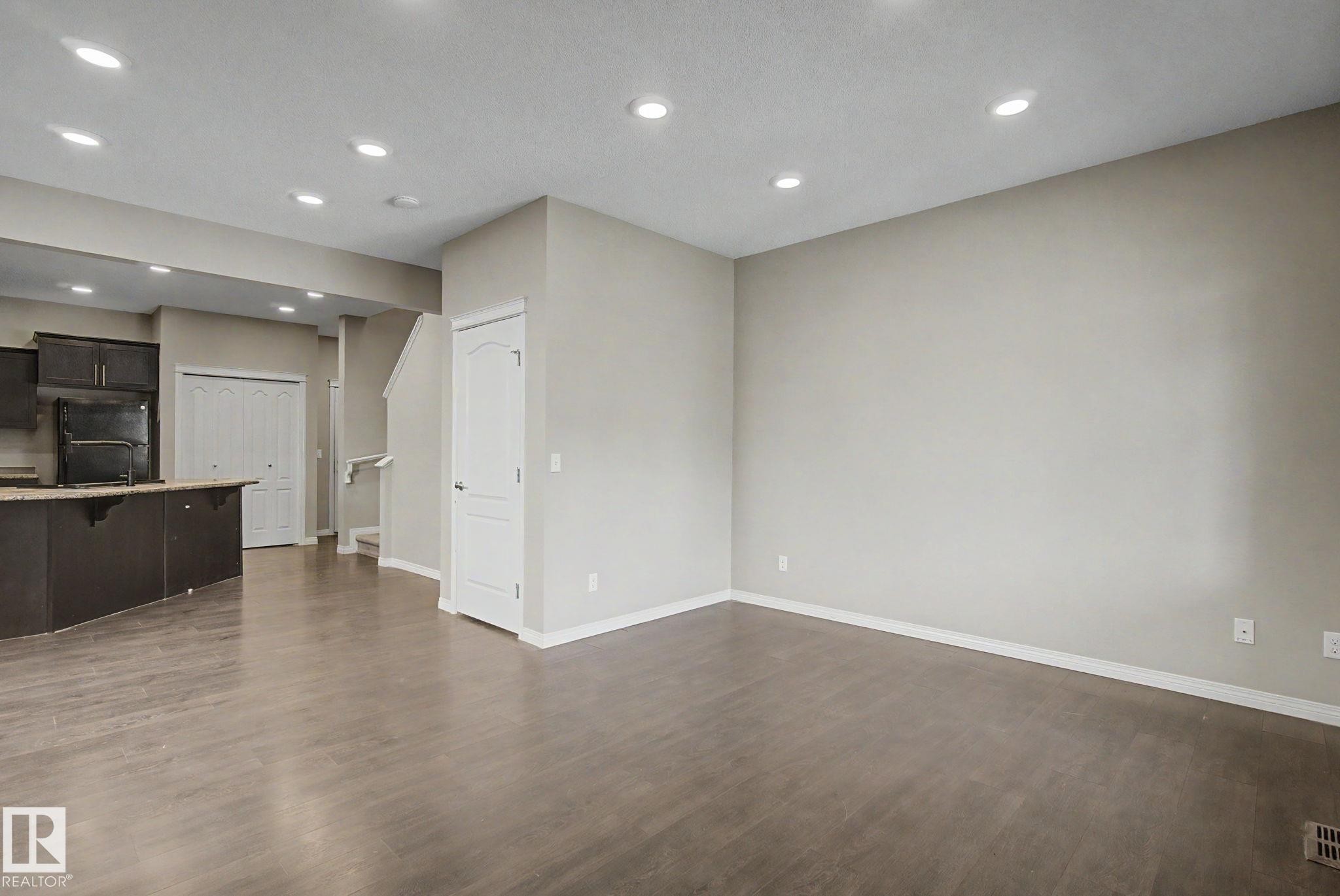 Expansive open-concept living area featuring wood-finish flooring, recessed lighting, and light neutral wall tones - 315 Watt Boulevard Sw, Edmonton, AB - Indoor