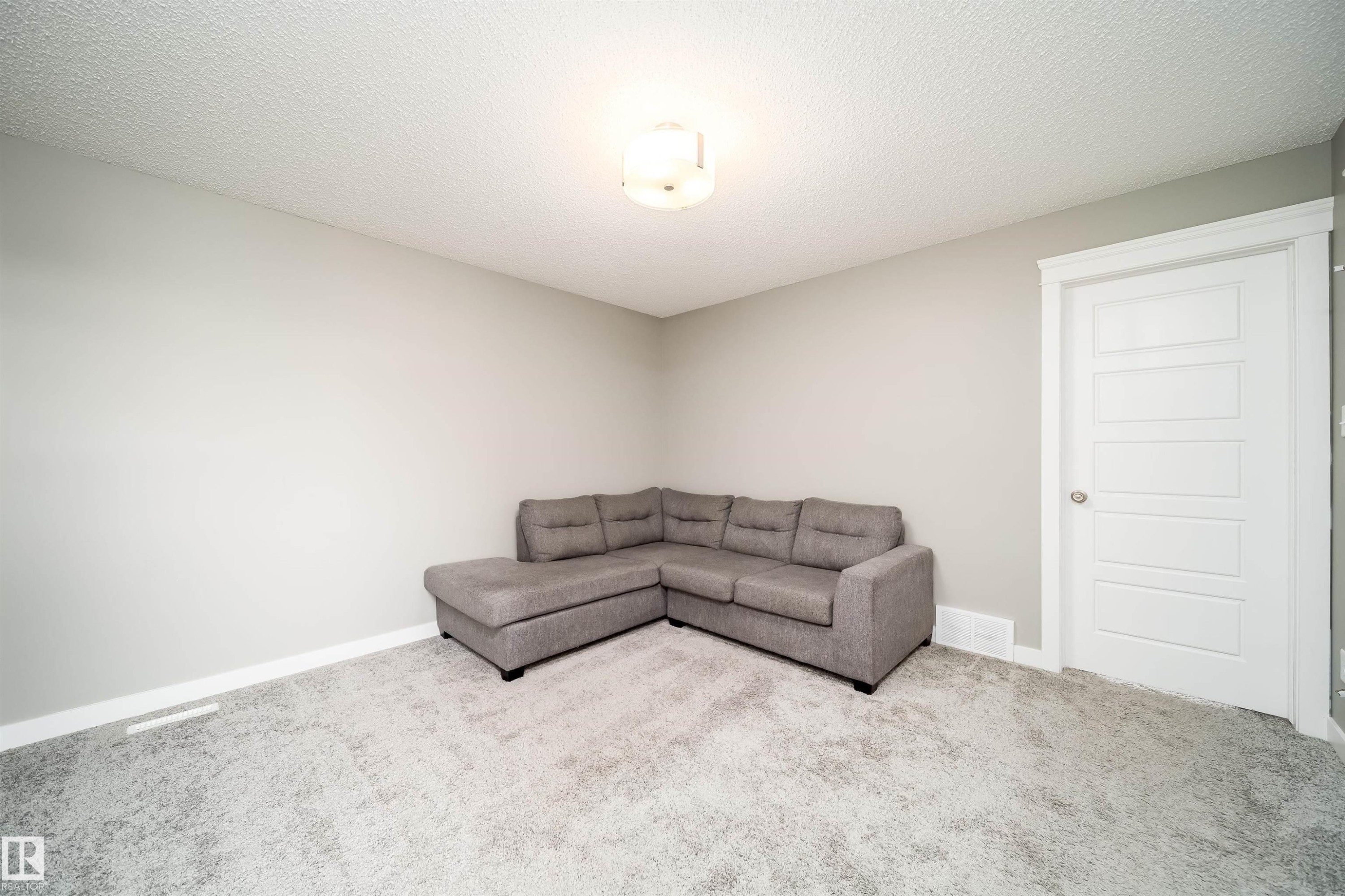 Carpeted room featuring light gray walls, white trim, and a five-panel interior door - 114 James Crescent, St. Albert, AB - Indoor