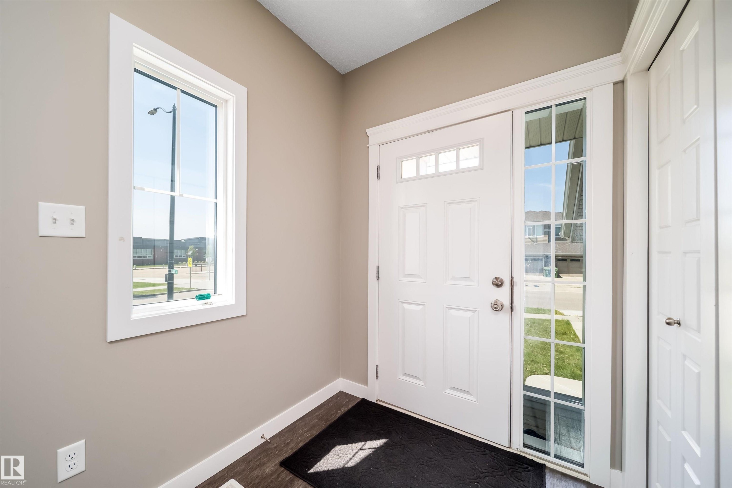Entryway featuring a white paneled door with transom windows, a grid-patterned sidelight, and a vertical window with white trim - 114 James Crescent, St. Albert, AB - Indoor Photo Showing Other Room