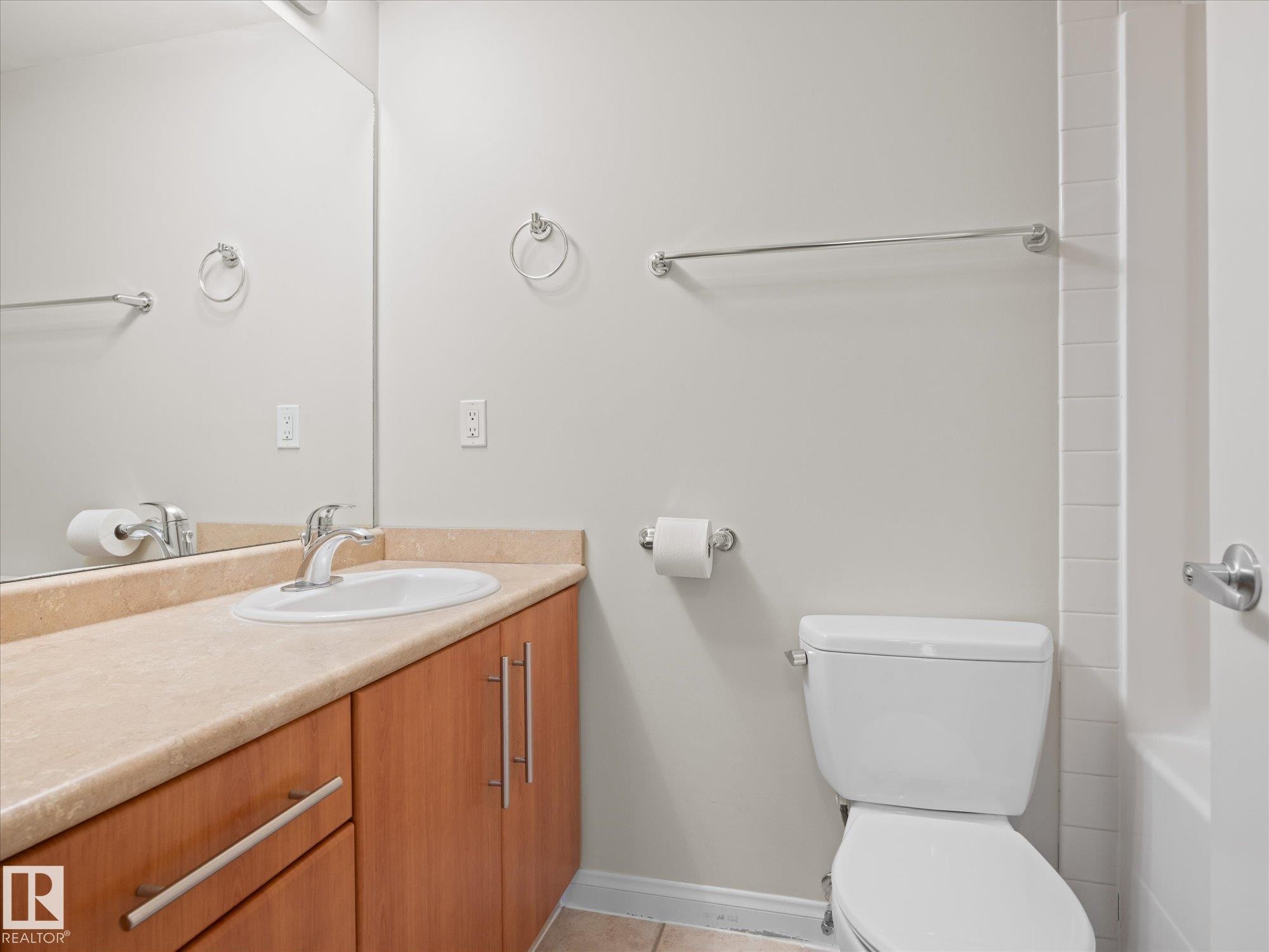 Bathroom featuring a wood-finish vanity with a light-toned countertop and integrated sink - #707 9819 104 St Nw, Edmonton, AB