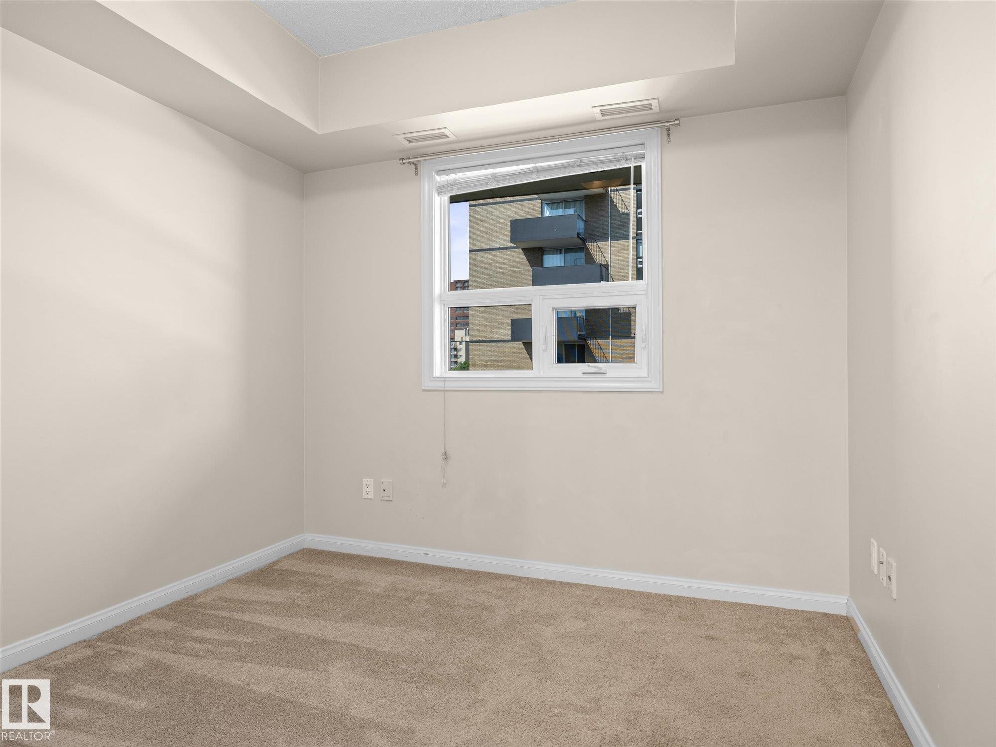 Carpeted room with a double-pane window, white trim, and neutral-toned walls - #707 9819 104 St Nw, Edmonton, AB