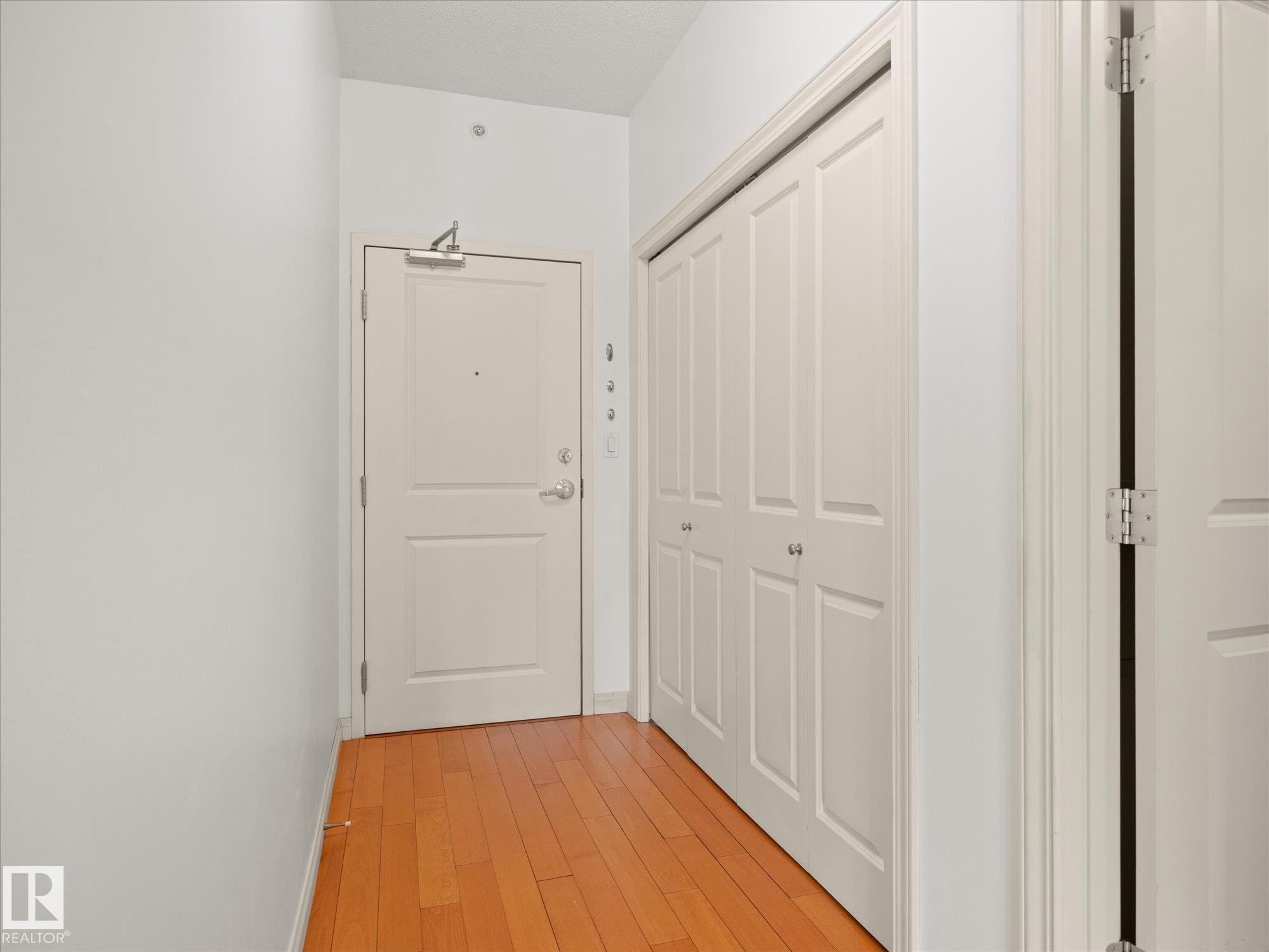 Entryway featuring wood-finish flooring, a paneled door, and a bi-fold closet - #707 9819 104 St Nw, Edmonton, AB
