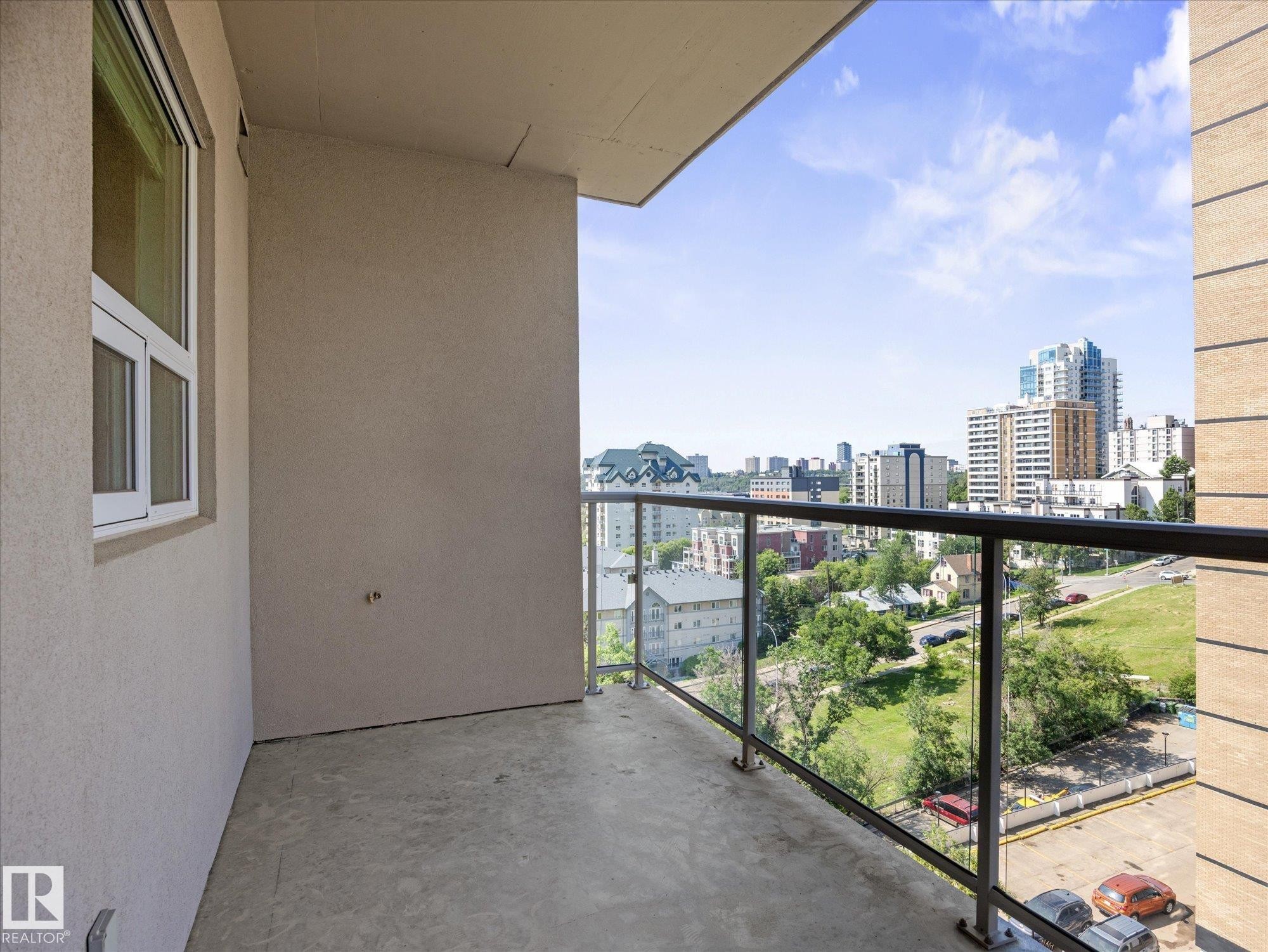 Private balcony featuring a glass and metal railing, concrete flooring, and a city backdrop - #707 9819 104 St Nw, Edmonton, AB