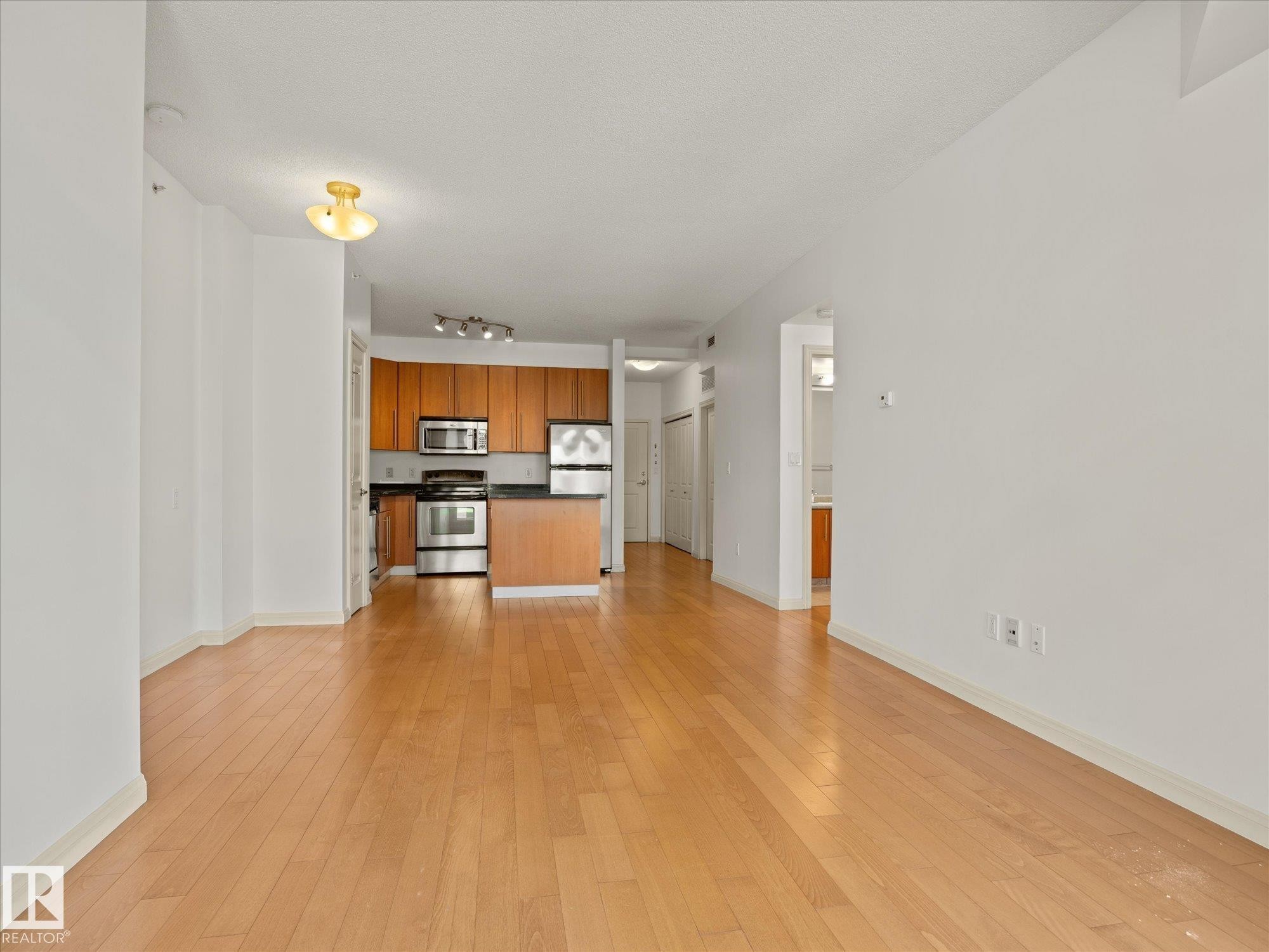 Open-concept living space featuring wood-finish flooring throughout - #707 9819 104 St Nw, Edmonton, AB