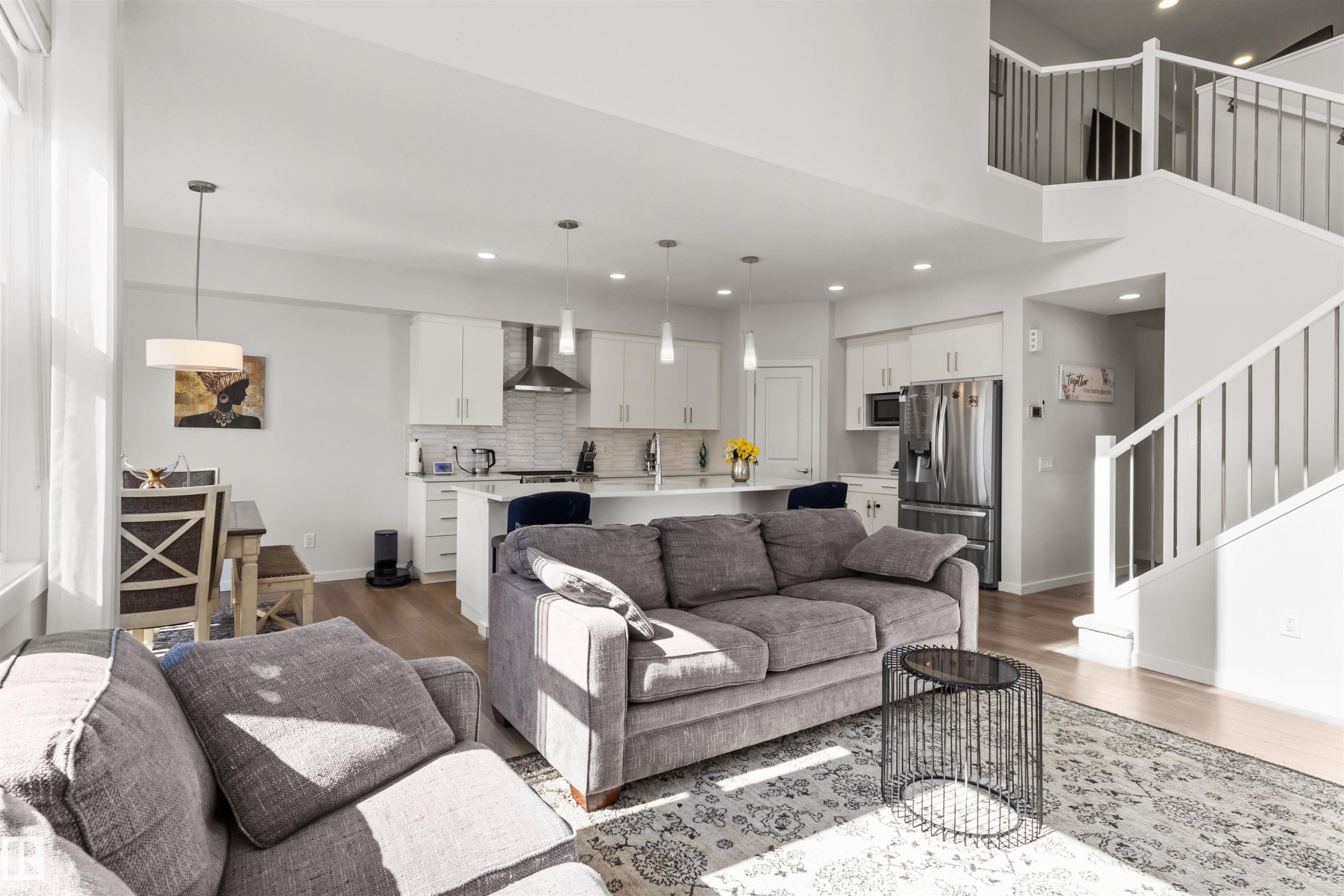 Open-concept living area featuring light wood-finish flooring, white walls, and a two-story ceiling - 1471 Plum Circle Sw, Edmonton, AB - Indoor Photo Showing Living Room