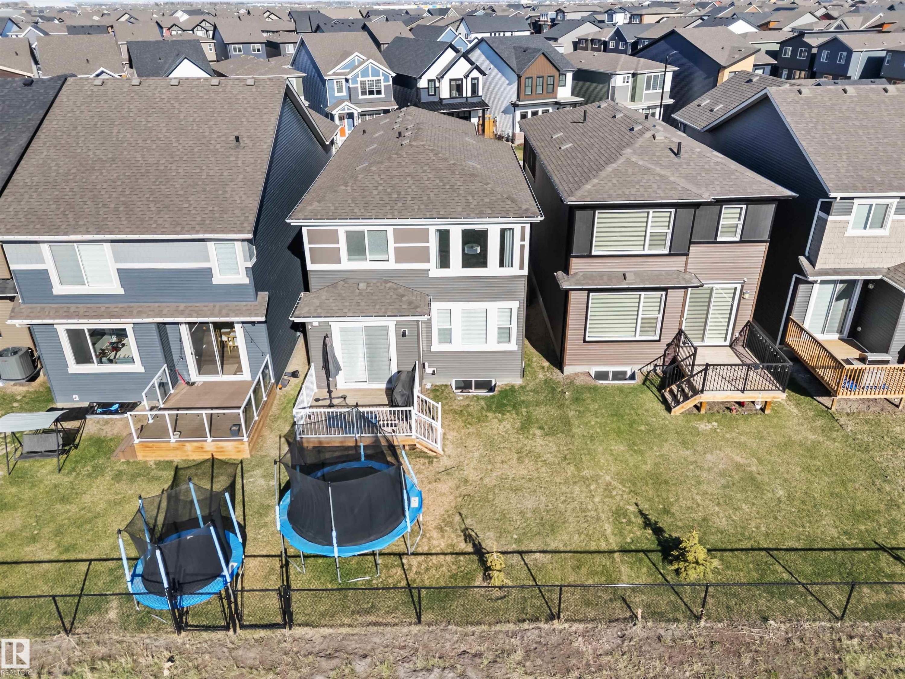 Rear exterior featuring a ground-level deck, sliding glass door, and multiple windows with horizontal blinds - 1471 Plum Circle Sw, Edmonton, AB - Outdoor