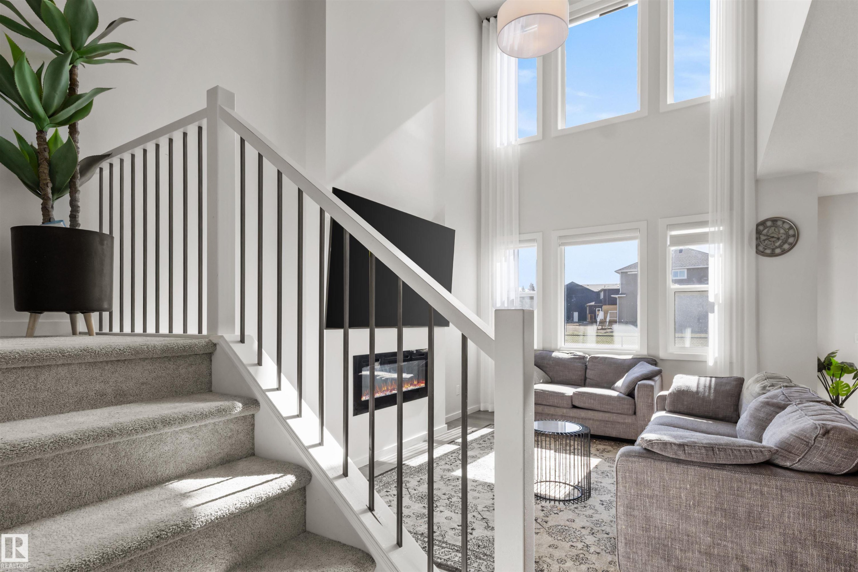 Interior staircase featuring carpeted treads and risers, white newel posts, and black metal balusters - 1471 Plum Circle Sw, Edmonton, AB - Indoor