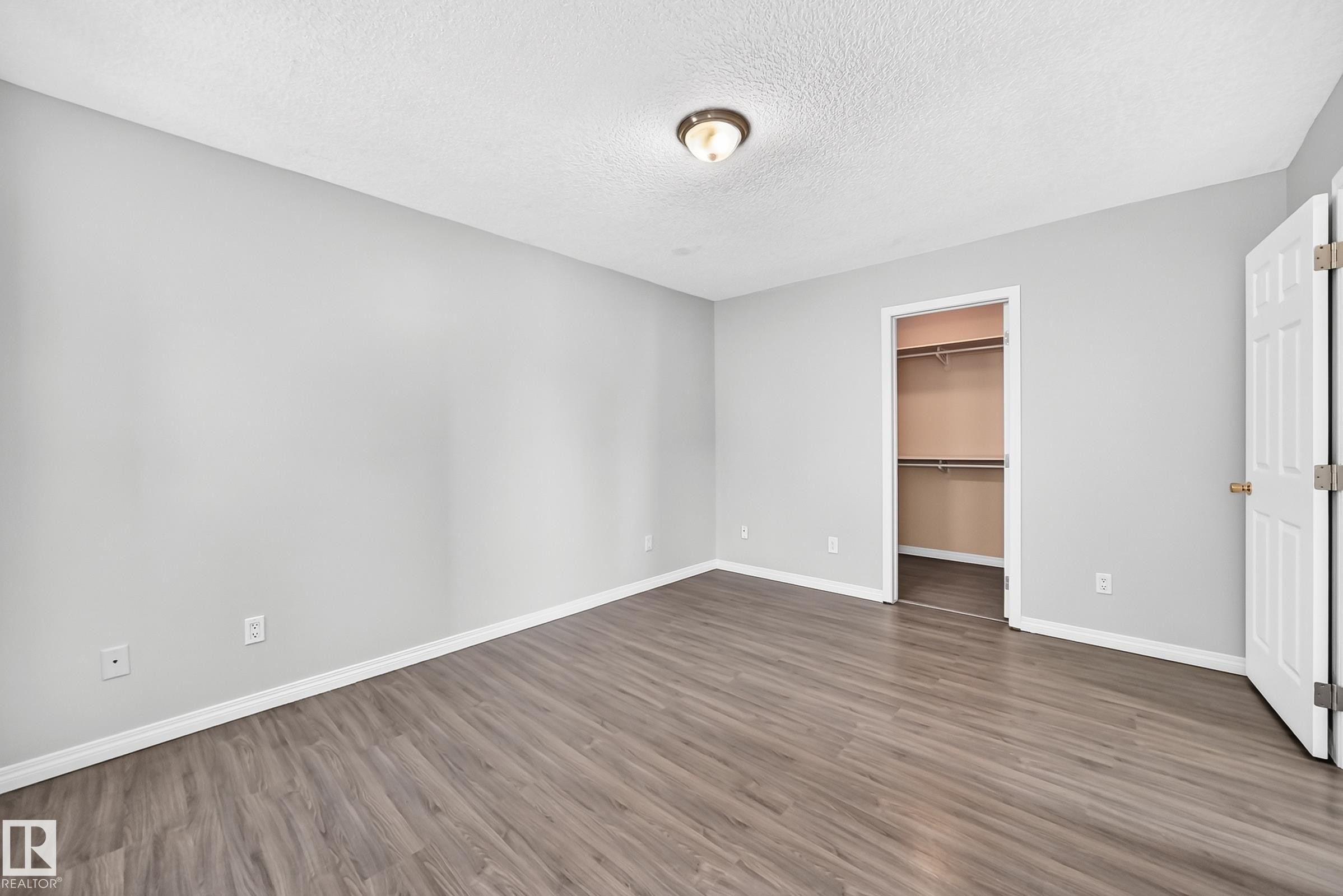 Spacious room featuring wood-finish flooring, light gray wall paint, and white baseboards - 9333 103A Avenue Nw, Edmonton, AB - Indoor Photo Showing Other Room