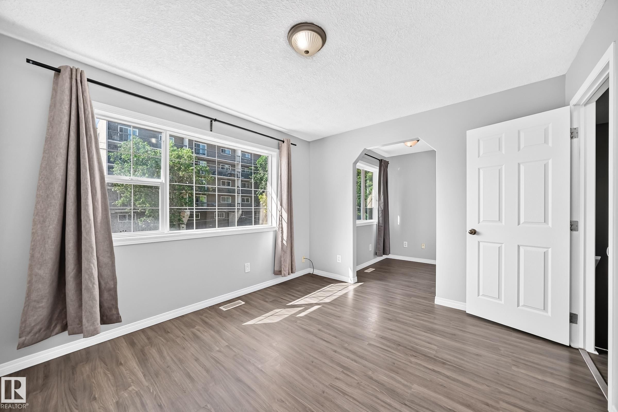Bright interior space featuring wood-finish flooring, light gray wall paint, and white trim - 9333 103A Avenue Nw, Edmonton, AB - Indoor Photo Showing Other Room