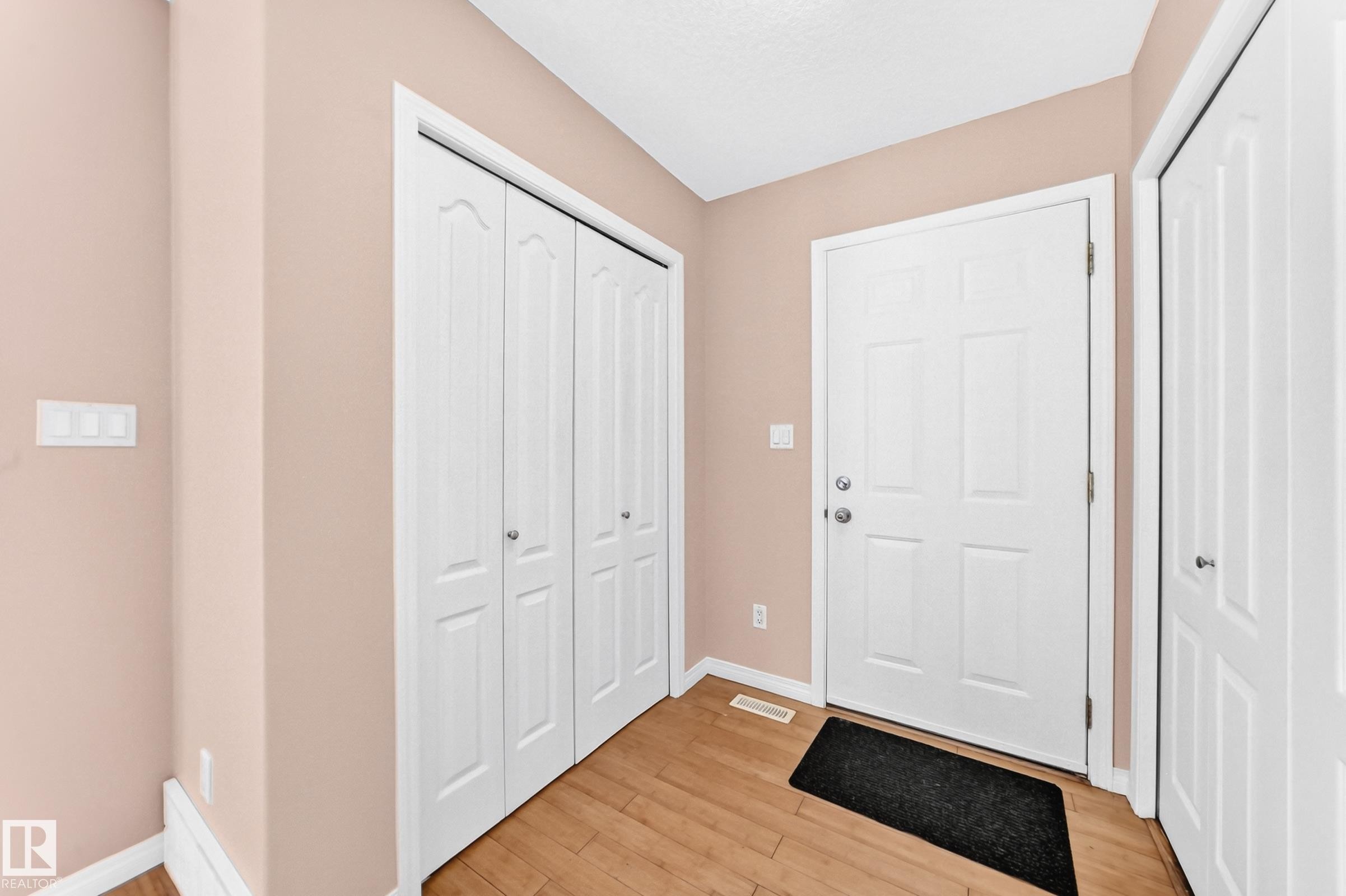 Entryway featuring wood-finish flooring, a white paneled entry door, and bi-fold closet doors - 9333 103A Avenue Nw, Edmonton, AB - Indoor Photo Showing Other Room