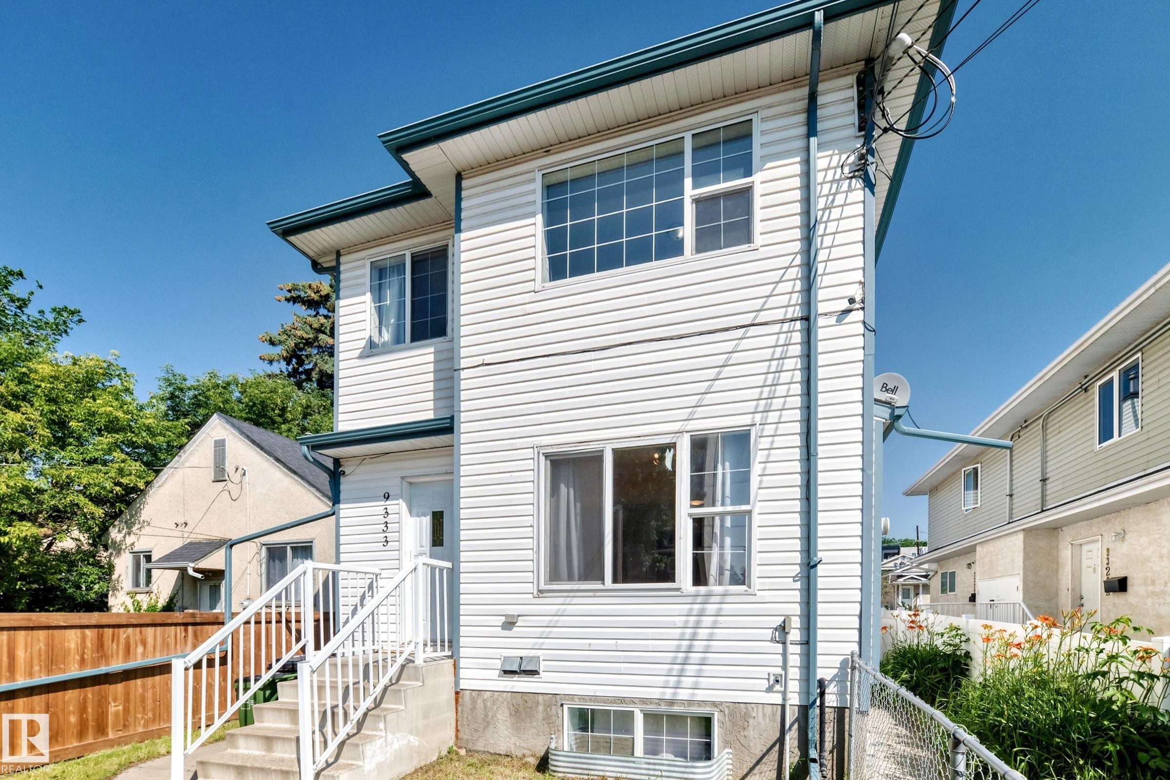 Two-story residence featuring horizontal white siding and contrasting dark green fascia - 9333 103A Avenue Nw, Edmonton, AB - Outdoor