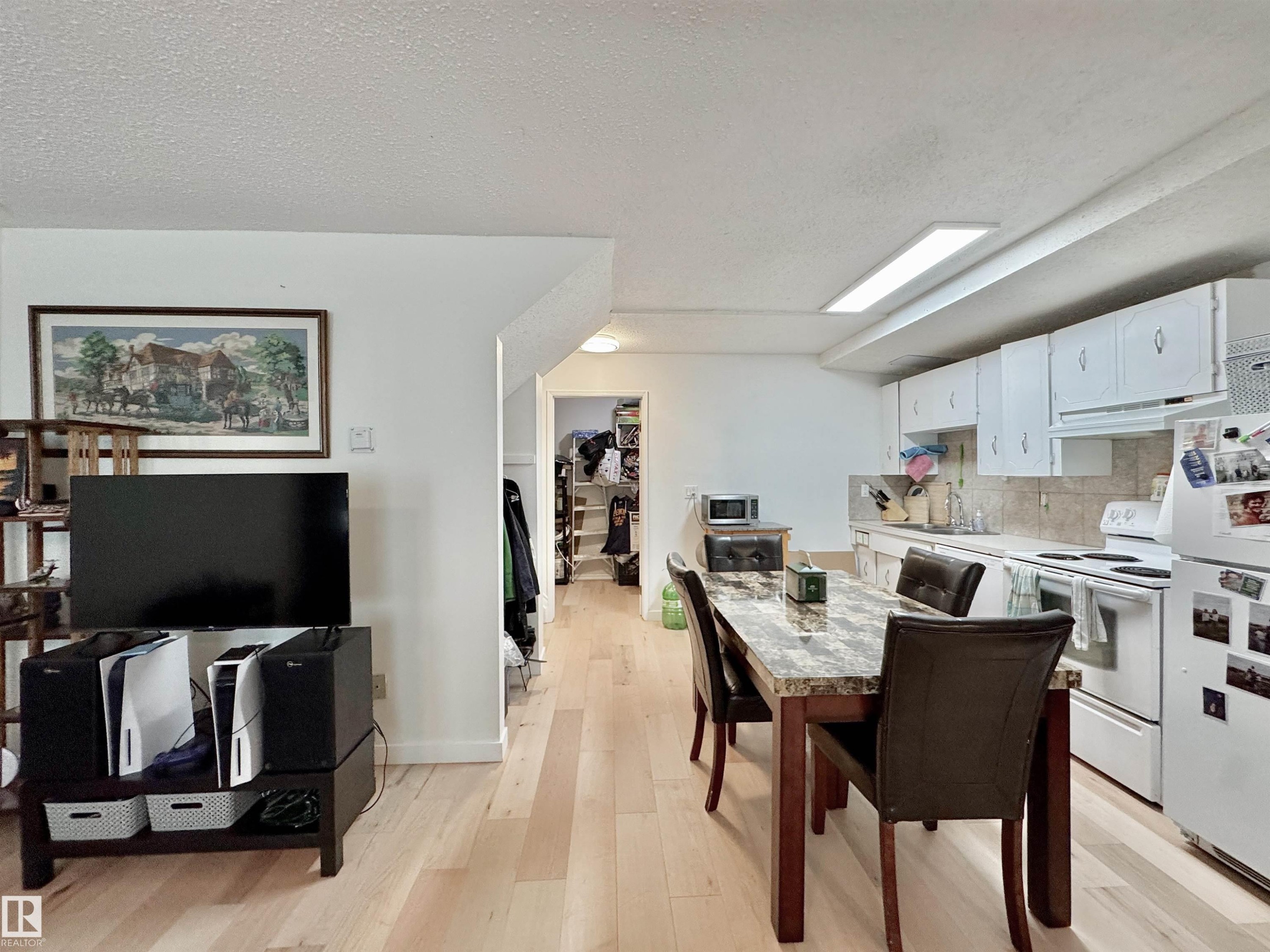Kitchen area featuring white cabinetry, light-toned backsplash, white appliances, and linear overhead lighting - #29 13580 38 St Nw, Edmonton, AB - Indoor
