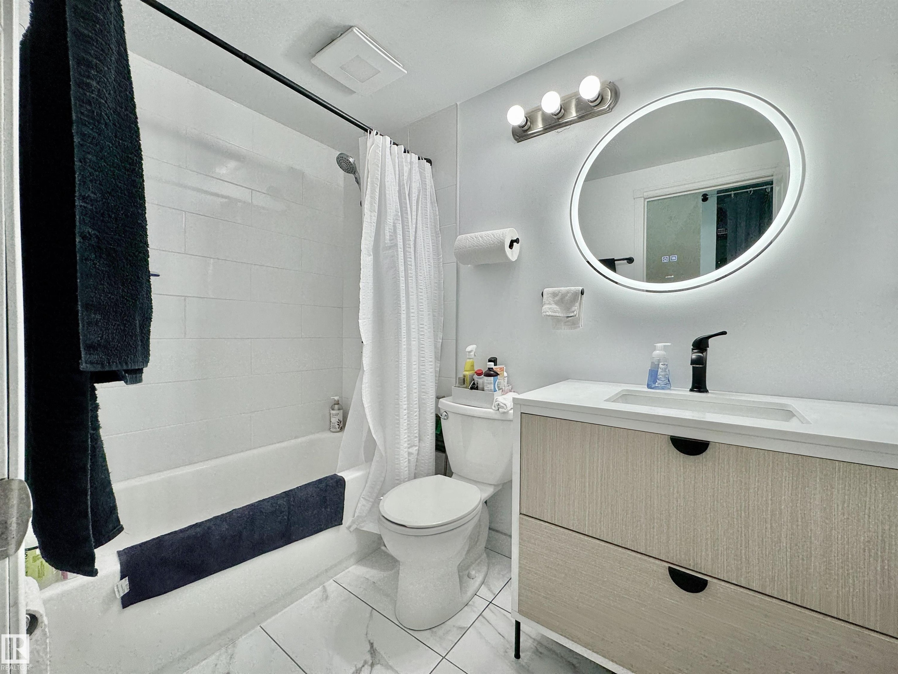 Modern bathroom featuring a contemporary vanity with two drawers, a white countertop, and a black faucet - #29 13580 38 St Nw, Edmonton, AB - Indoor Photo Showing Bathroom