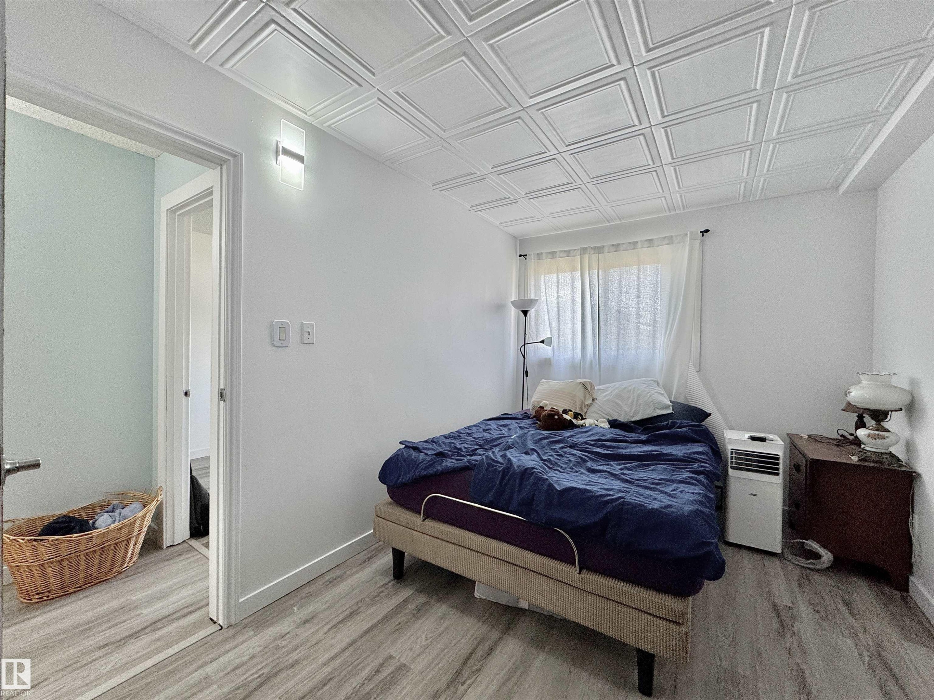 Room featuring a decorative coffered ceiling, light wood-finish flooring, white walls, and a window with sheer curtains - #29 13580 38 St Nw, Edmonton, AB - Indoor Photo Showing Bedroom