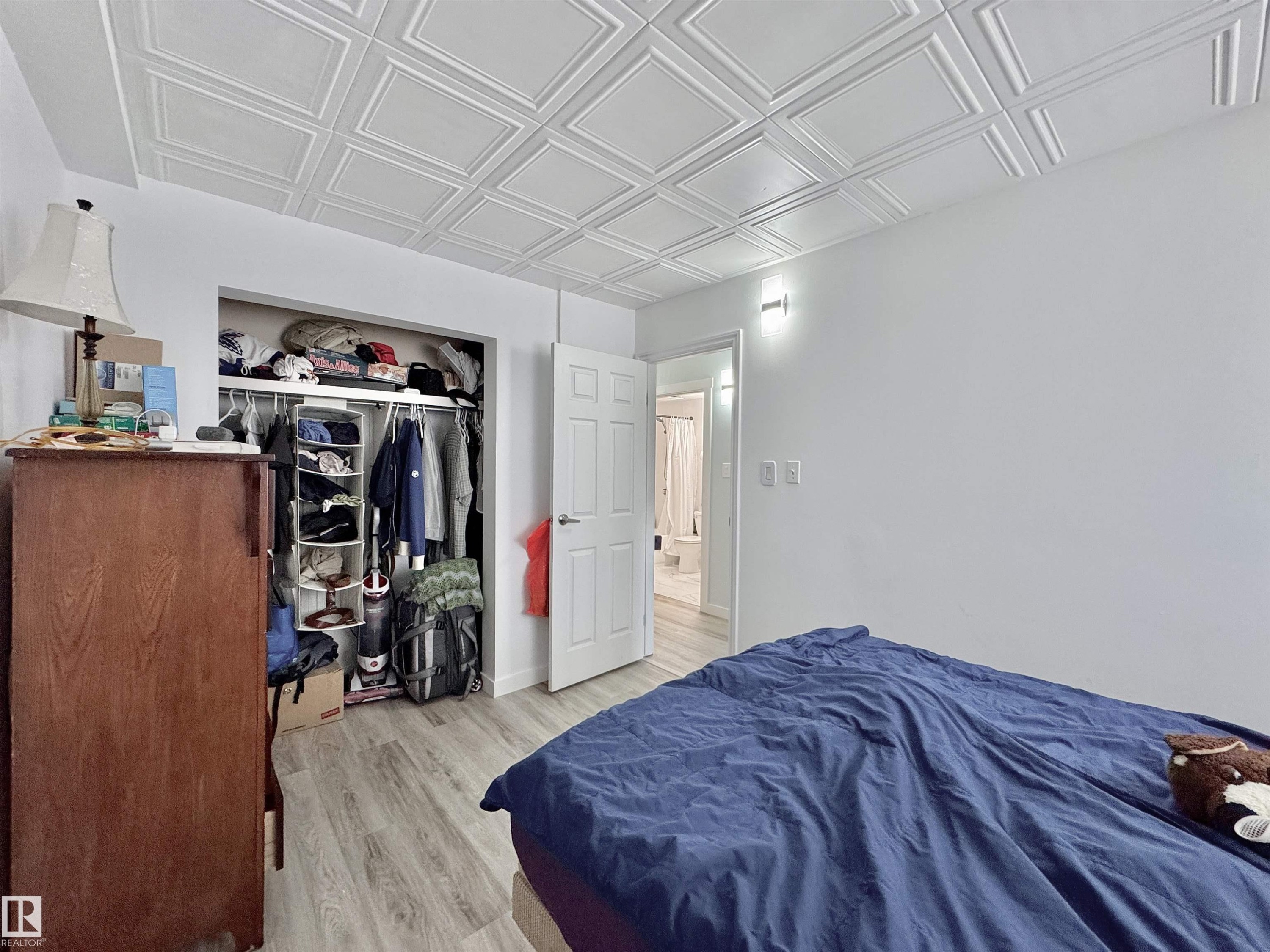 Room featuring wood-finish flooring, white walls, and a white pressed tin ceiling - #29 13580 38 St Nw, Edmonton, AB - Indoor Photo Showing Bedroom
