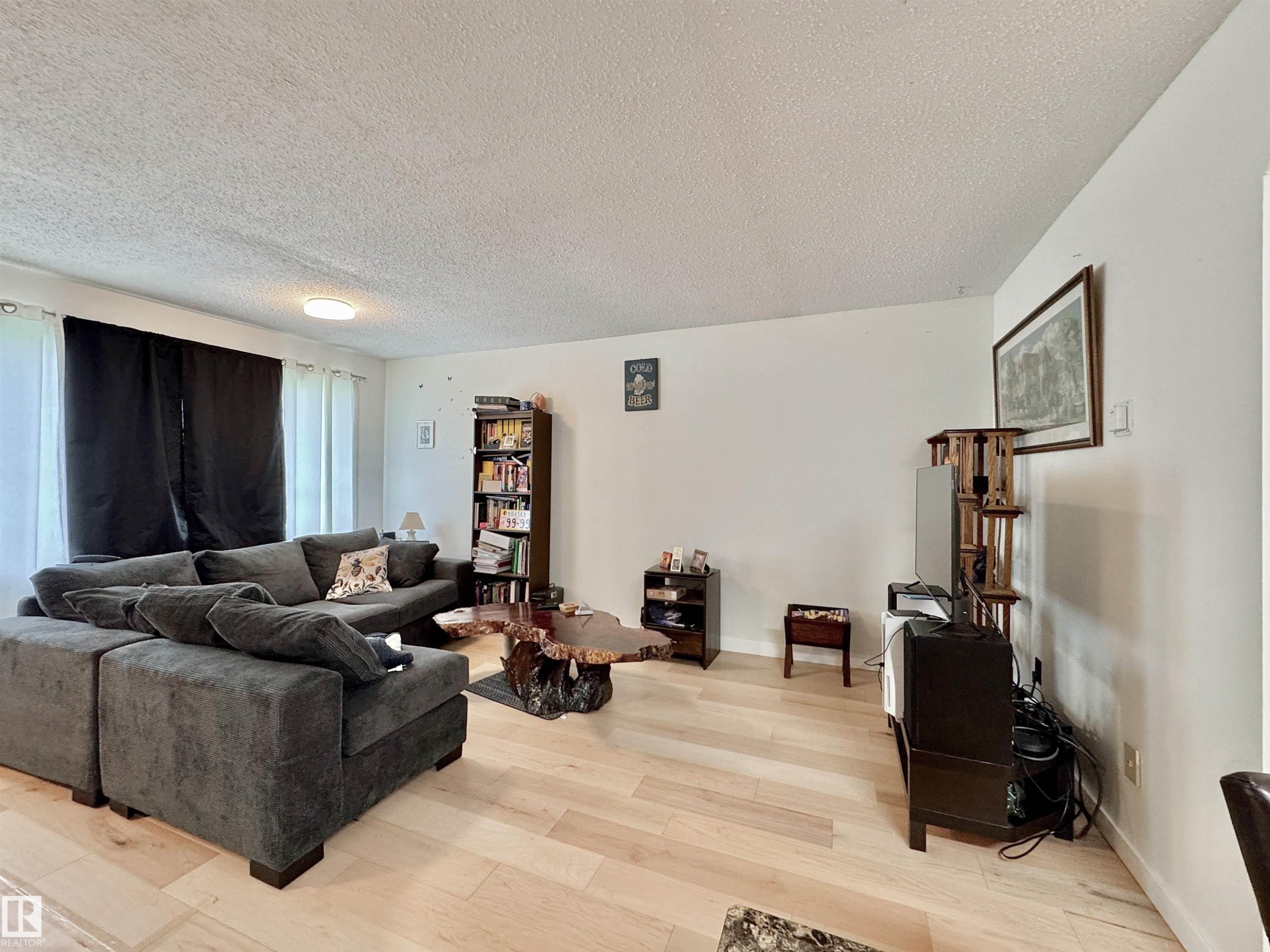 Bright living area featuring wood-finish flooring and white walls - #29 13580 38 St Nw, Edmonton, AB - Indoor Photo Showing Living Room