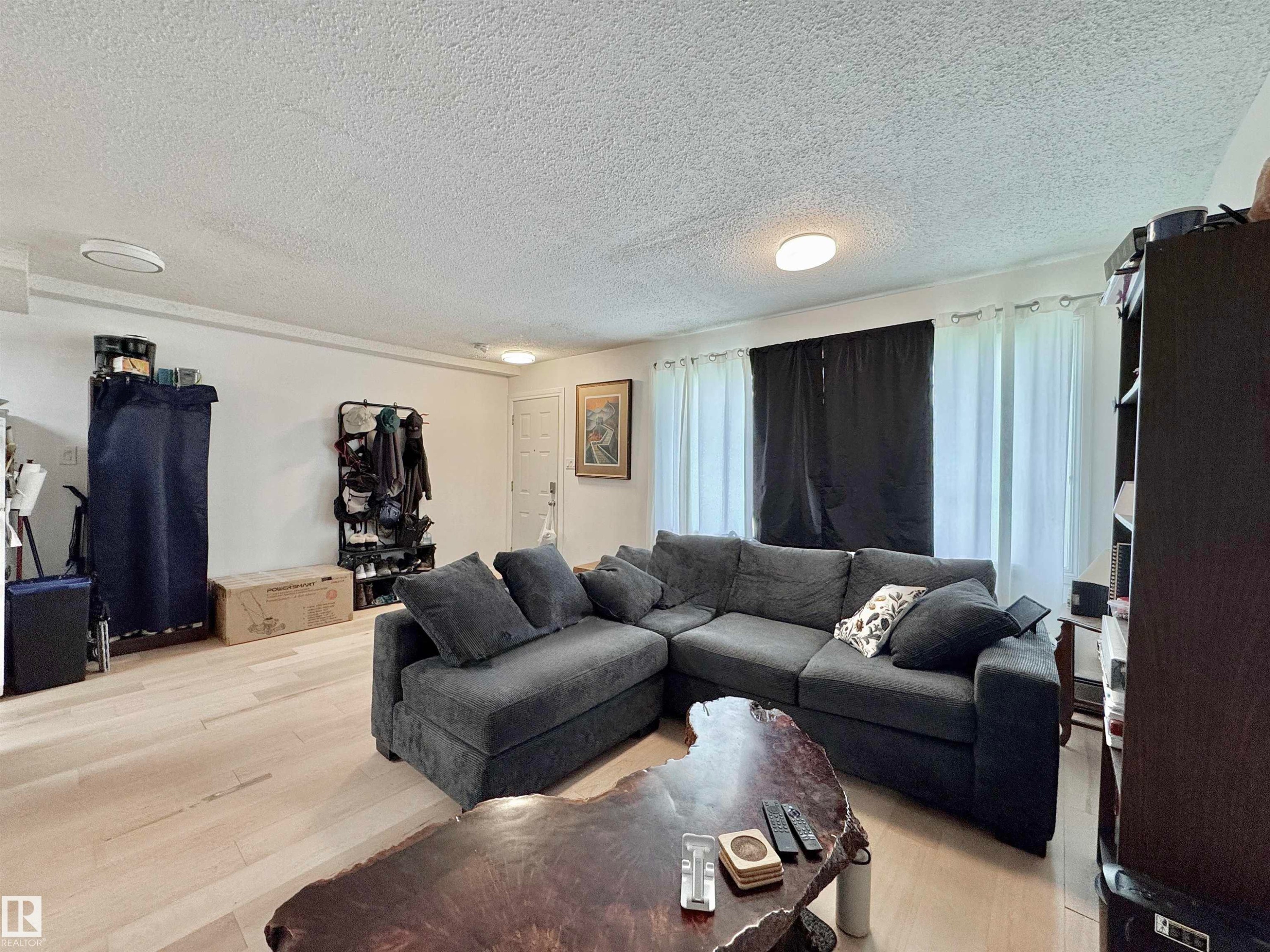 Spacious living area featuring light wood-finish flooring and ample natural light from multiple windows - #29 13580 38 St Nw, Edmonton, AB - Indoor Photo Showing Living Room
