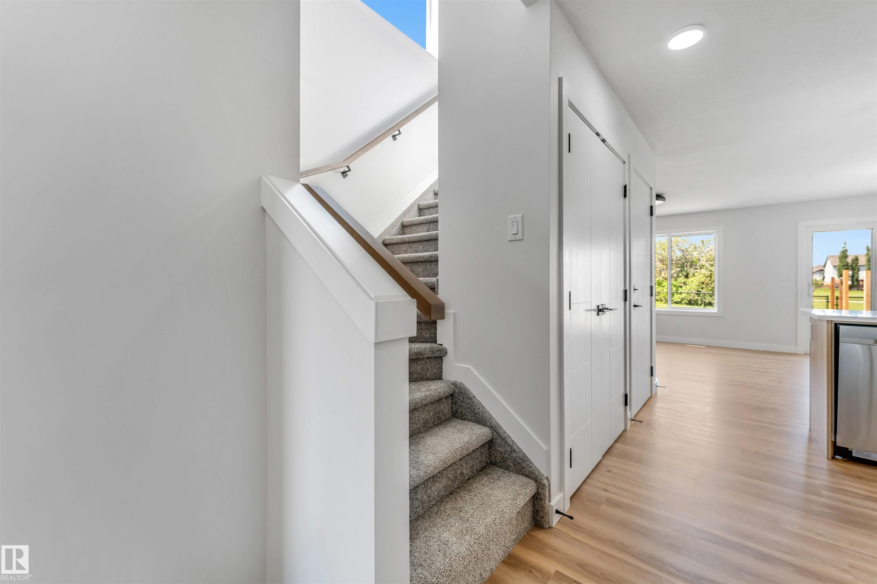 Staircase with carpeted treads and a wooden handrail, featuring white trim and walls - 1712 27 St Nw, Edmonton, AB - Indoor Photo Showing Other Room