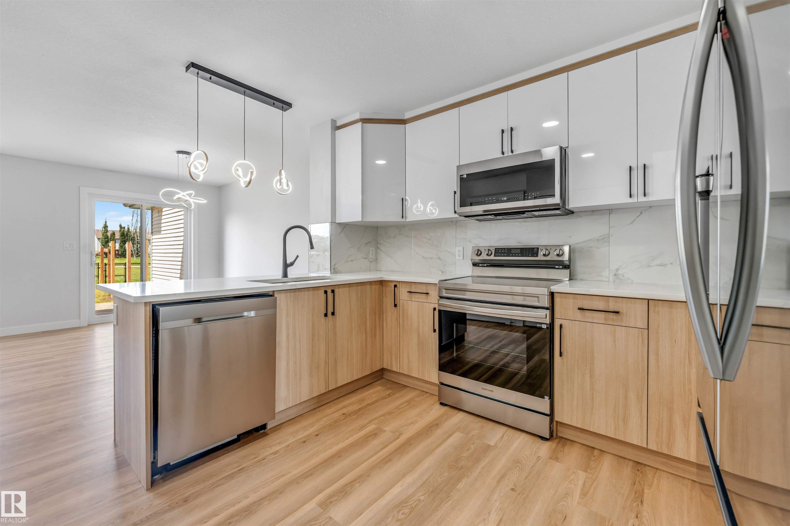 Contemporary kitchen featuring an integrated island, stainless steel appliances, light wood-finish flooring, white upper cabinetry, and a patterned backsplash - 1712 27 St Nw, Edmonton, AB - Indoor Photo Showing Kitchen With Upgraded Kitchen