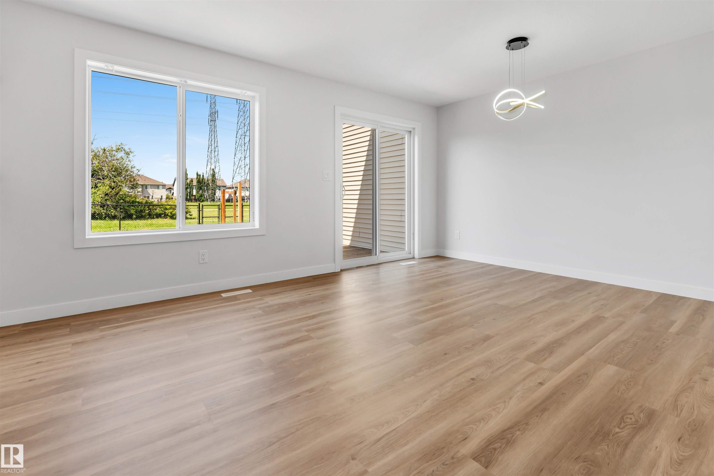 Open-concept room featuring light wood-finish flooring and a contemporary pendant light fixture - 1712 27 St Nw, Edmonton, AB - Indoor Photo Showing Other Room