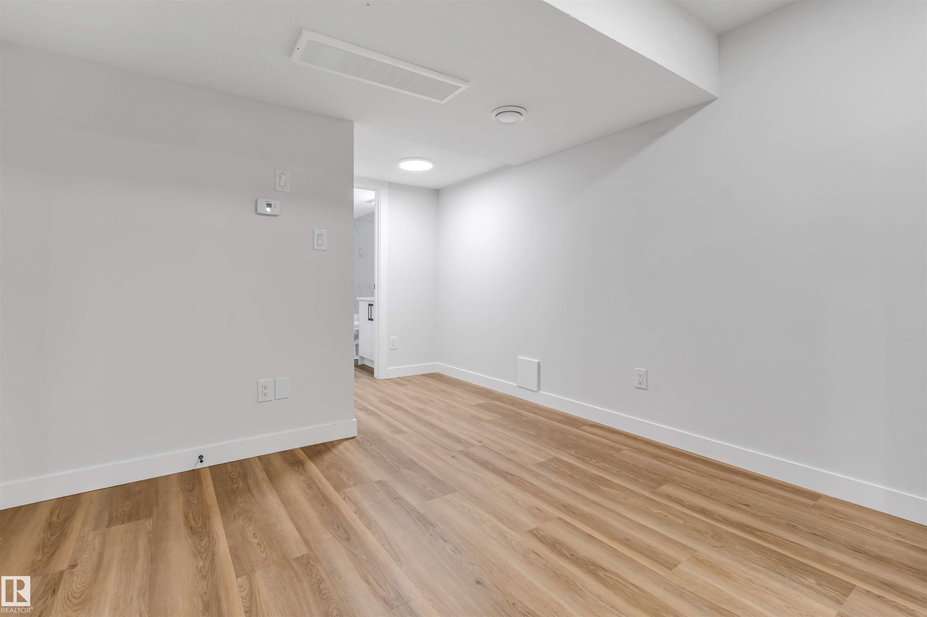 Open room featuring light wood-finish flooring, white baseboards, and white walls - 1712 27 St Nw, Edmonton, AB - Indoor Photo Showing Other Room