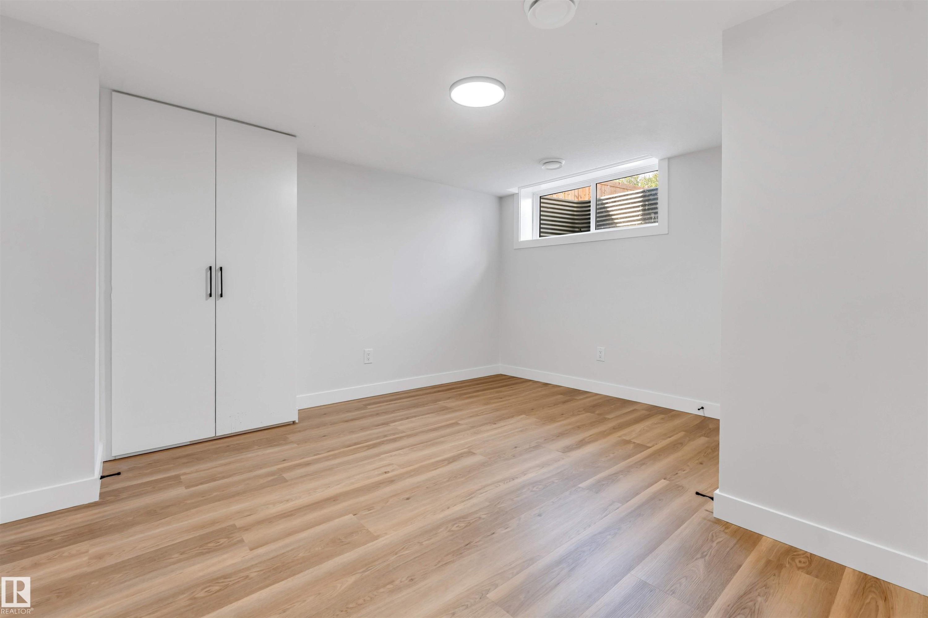 Room featuring wood-finish flooring, white walls, and a recessed window - 1712 27 St Nw, Edmonton, AB - Indoor Photo Showing Other Room