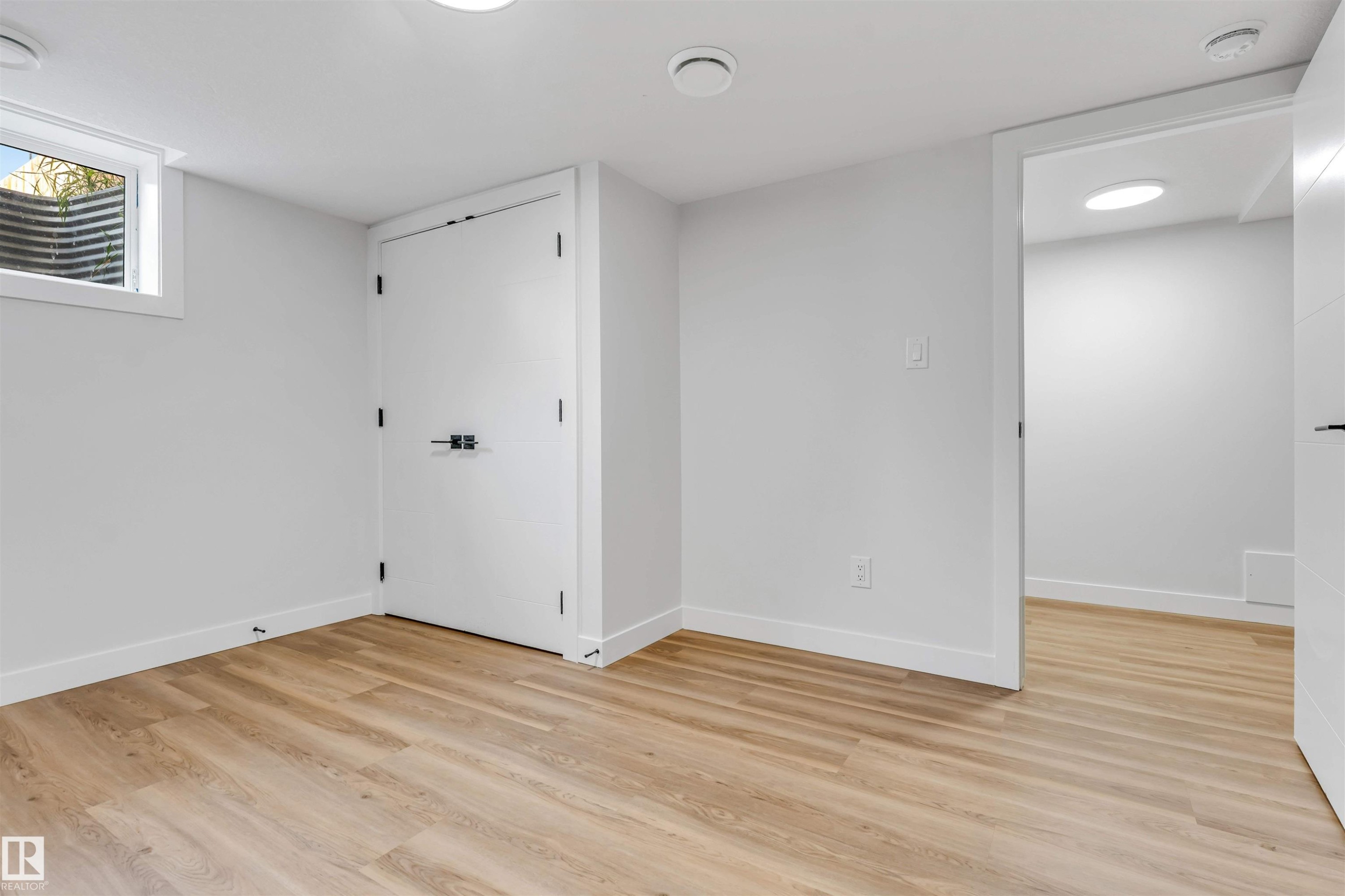 Finished room featuring wood-finish flooring, recessed lighting, and a window well - 1712 27 St Nw, Edmonton, AB - Indoor Photo Showing Other Room