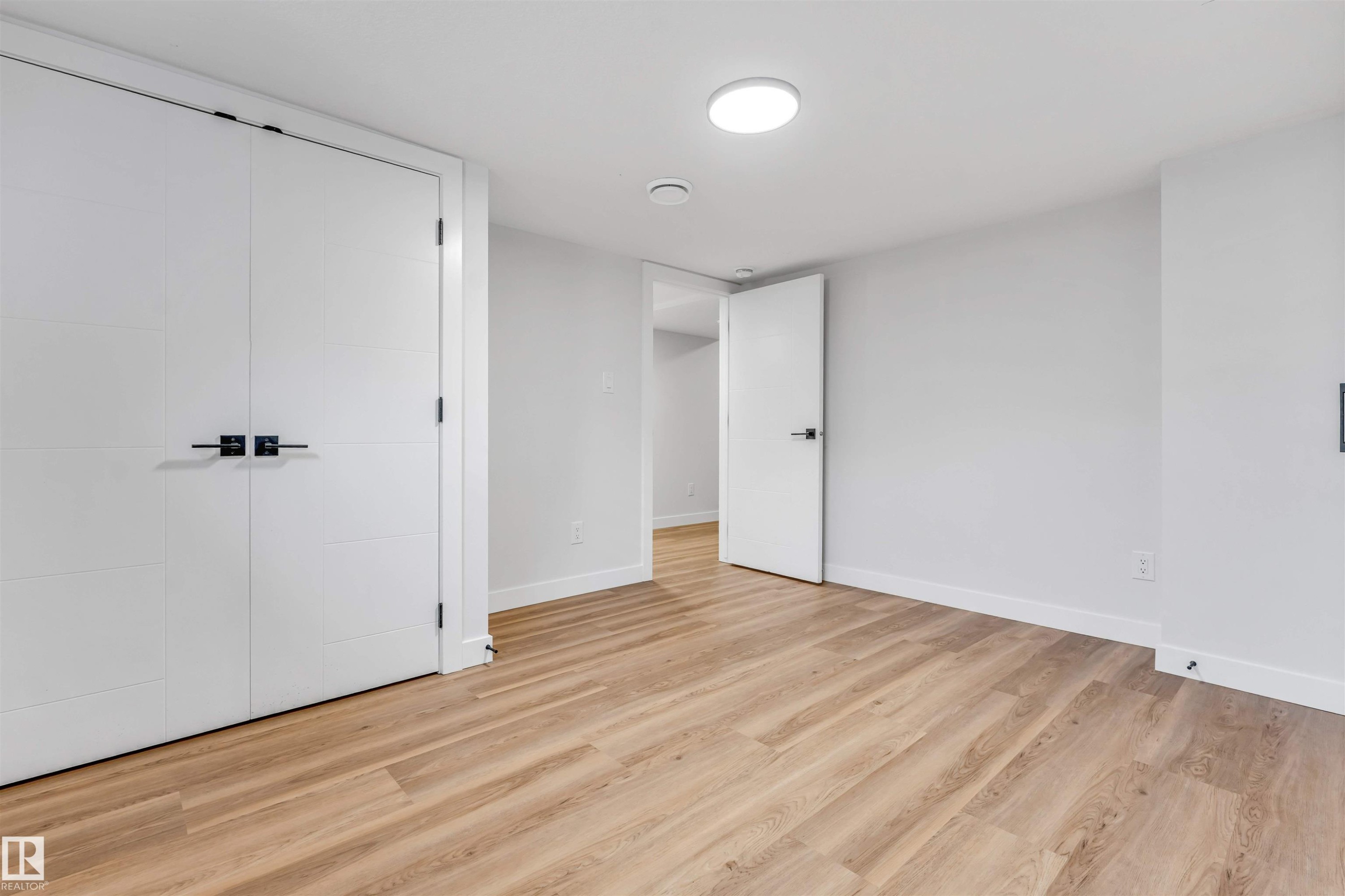 Bright interior space featuring light wood-finish flooring, white walls, and white baseboards - 1712 27 St Nw, Edmonton, AB - Indoor Photo Showing Other Room