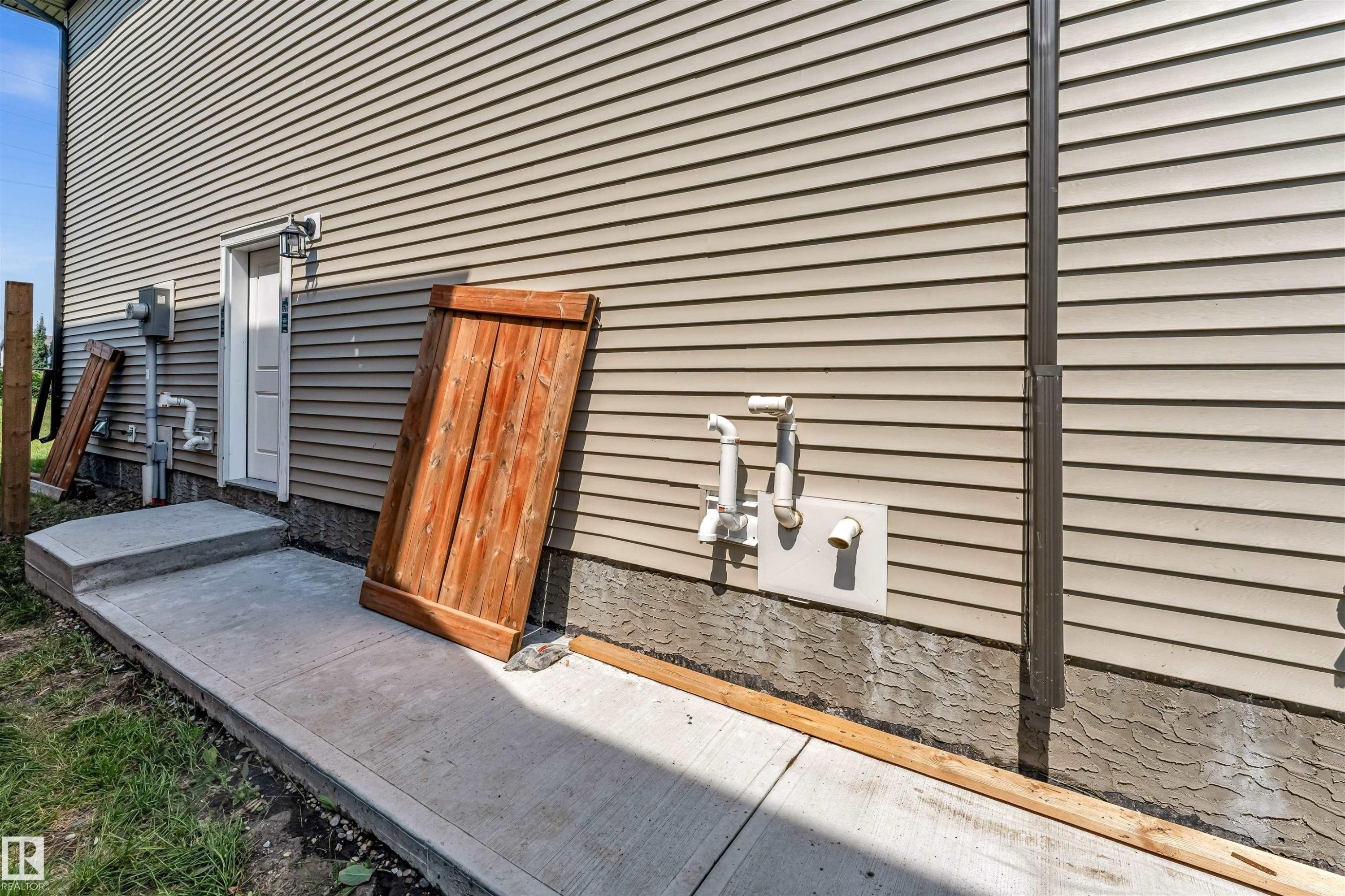 Exterior wall featuring light-colored horizontal siding and a concrete foundation - 1712 27 St Nw, Edmonton, AB - Outdoor With Exterior