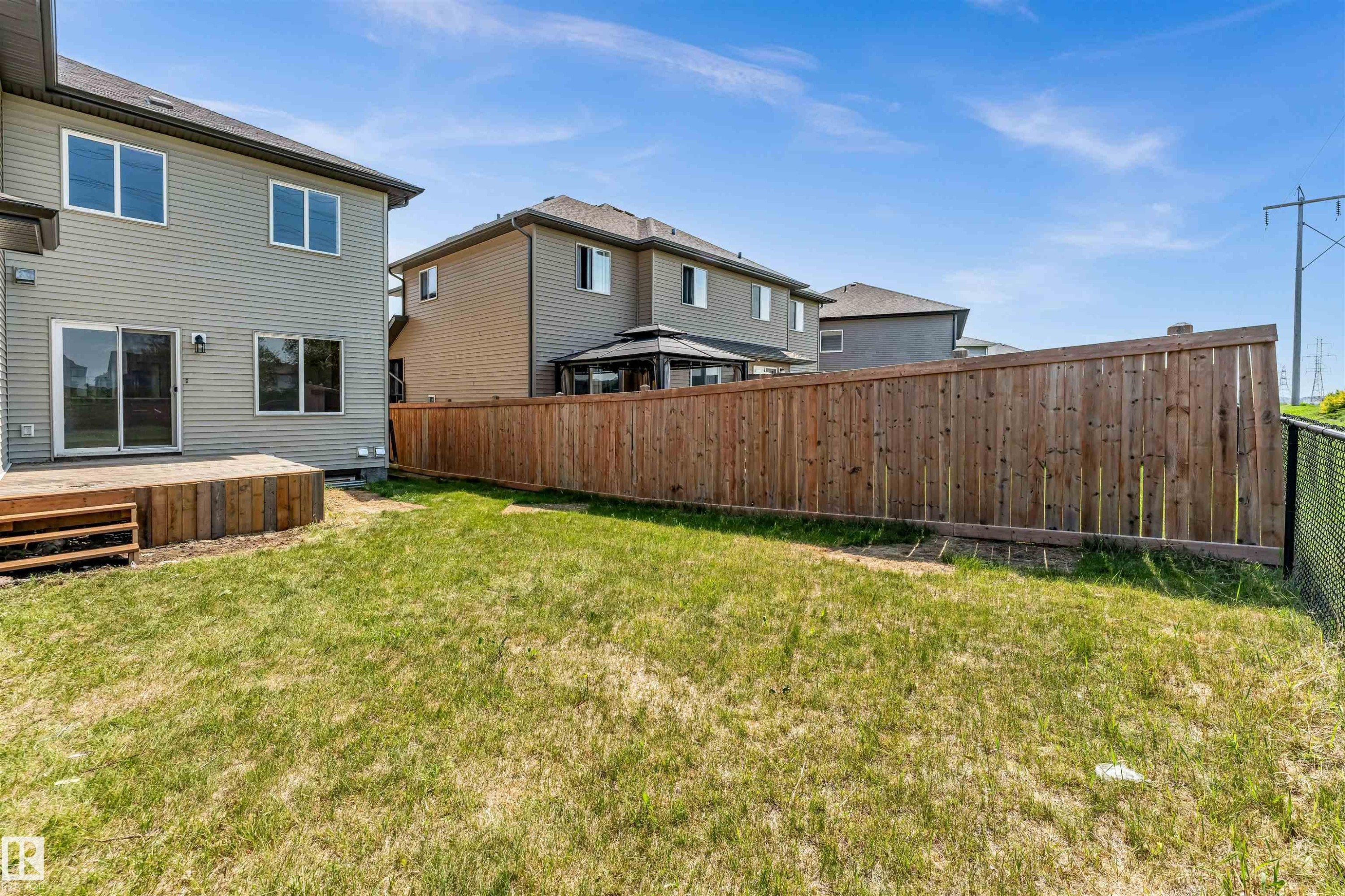 Expansive backyard featuring a wooden deck, sliding glass door, and a full privacy fence - 1712 27 St Nw, Edmonton, AB - Outdoor With Exterior