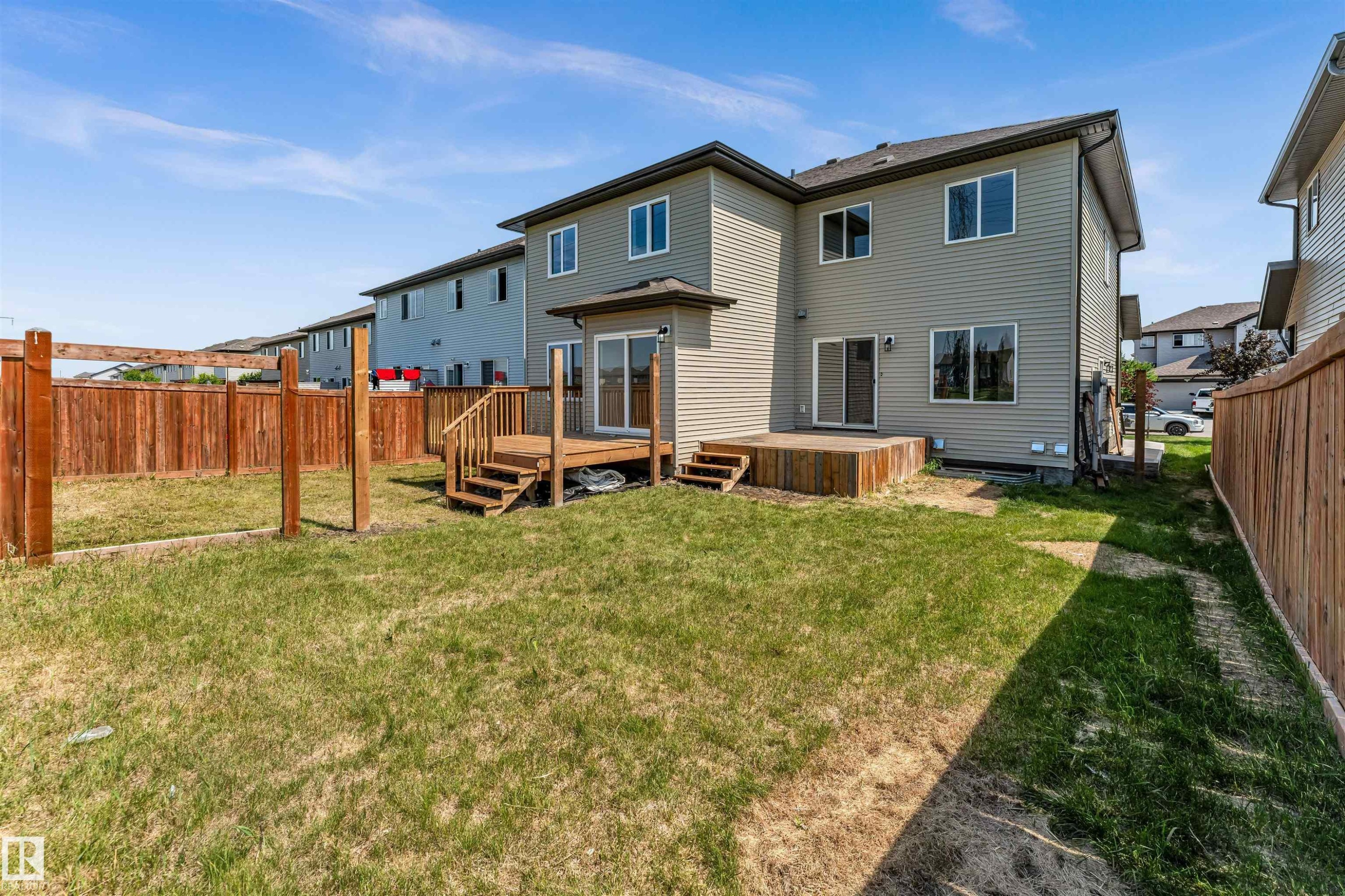 Expansive backyard with a wooden fence, featuring a multi-level deck, and sliding glass doors - 1712 27 St Nw, Edmonton, AB - Outdoor With Exterior