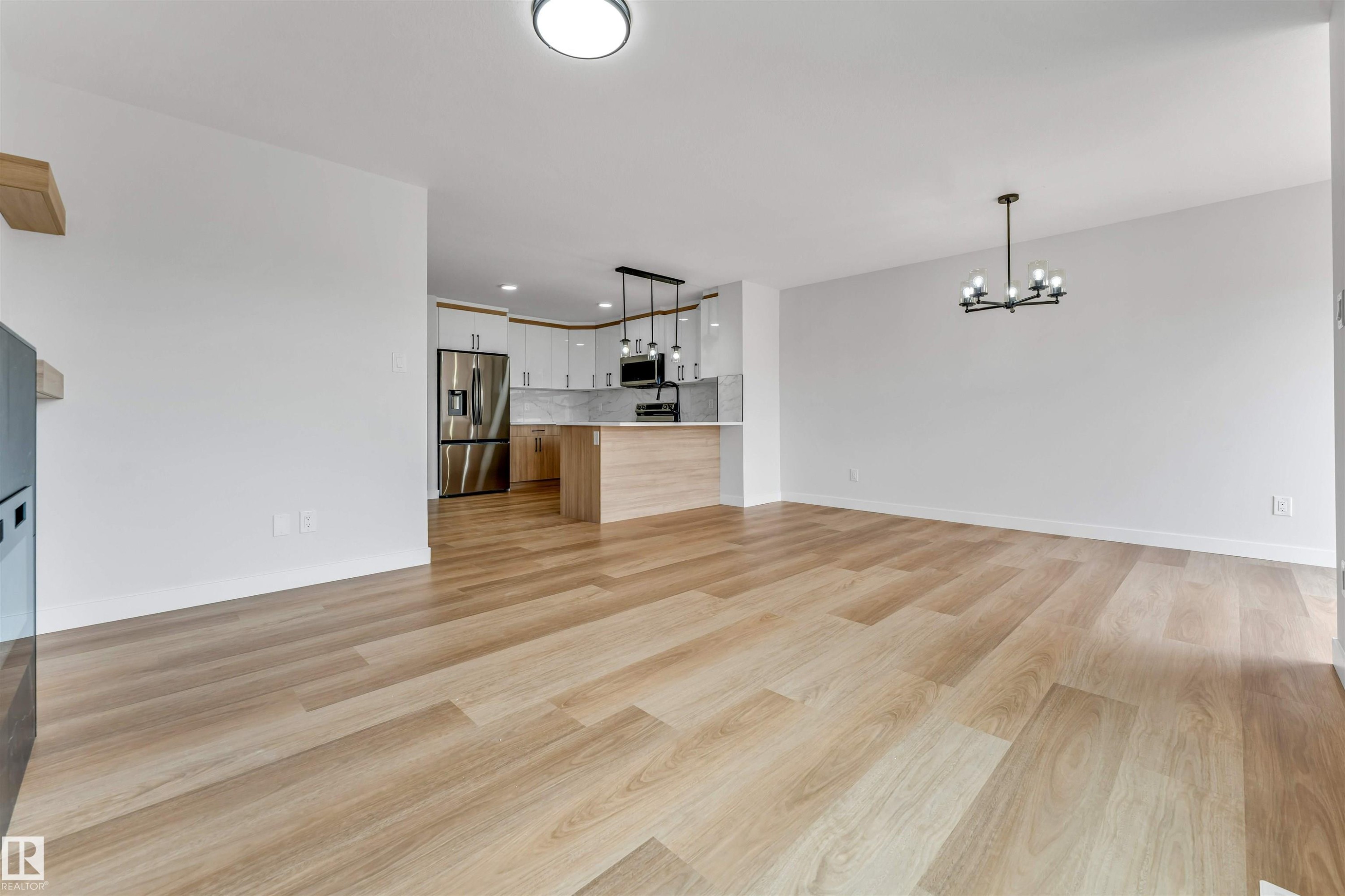 Open-concept living space featuring wood-finish flooring, recessed lighting, and a modern chandelier - 1714 27 St. Nw, Edmonton, AB - Indoor