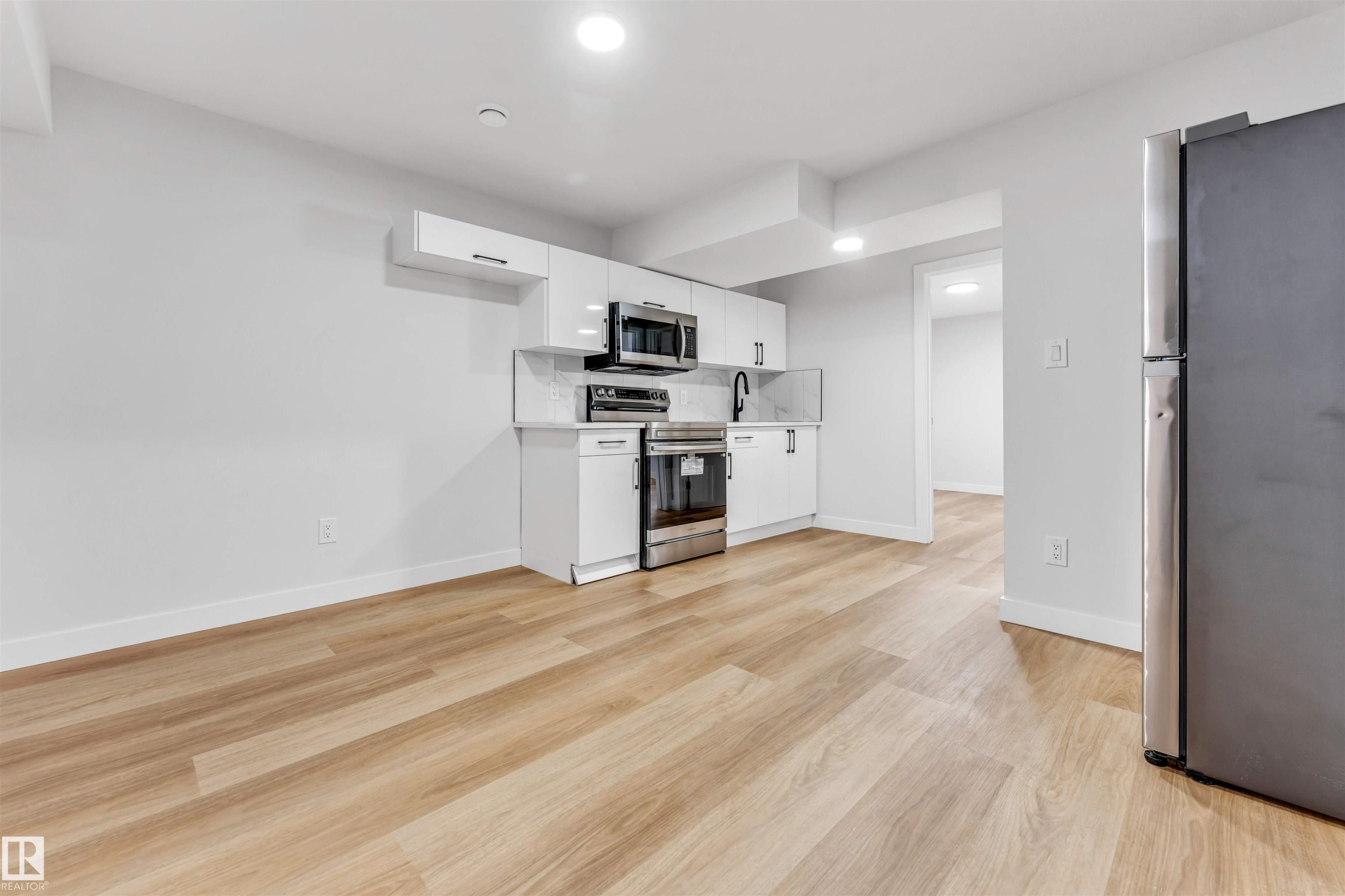 Open-concept room featuring wood-finish flooring, recessed lighting, and a modern kitchen area - 1714 27 St. Nw, Edmonton, AB - Indoor Photo Showing Kitchen