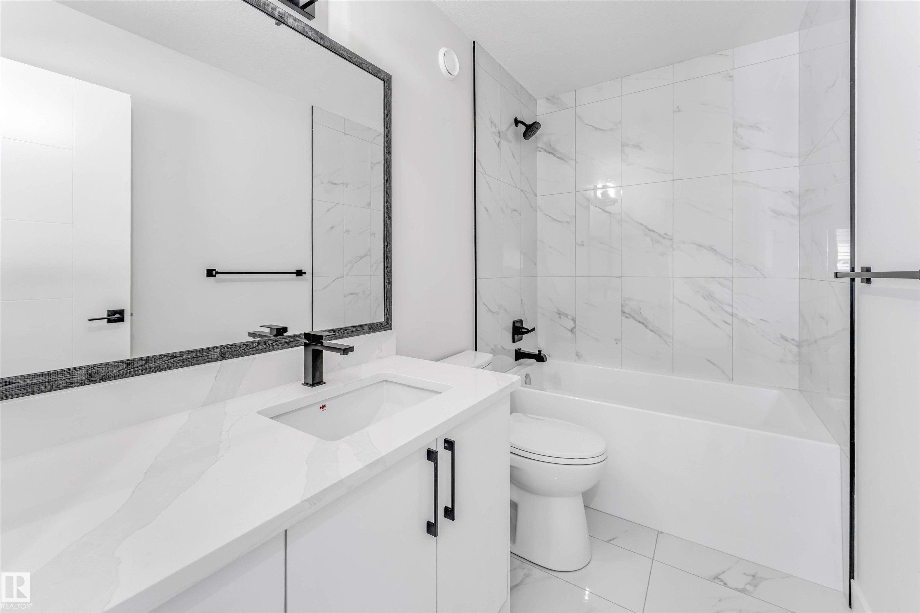 Bathroom featuring a white vanity with an integrated sink, black faucet, and a framed mirror - 1714 27 St. Nw, Edmonton, AB - Indoor Photo Showing Bathroom