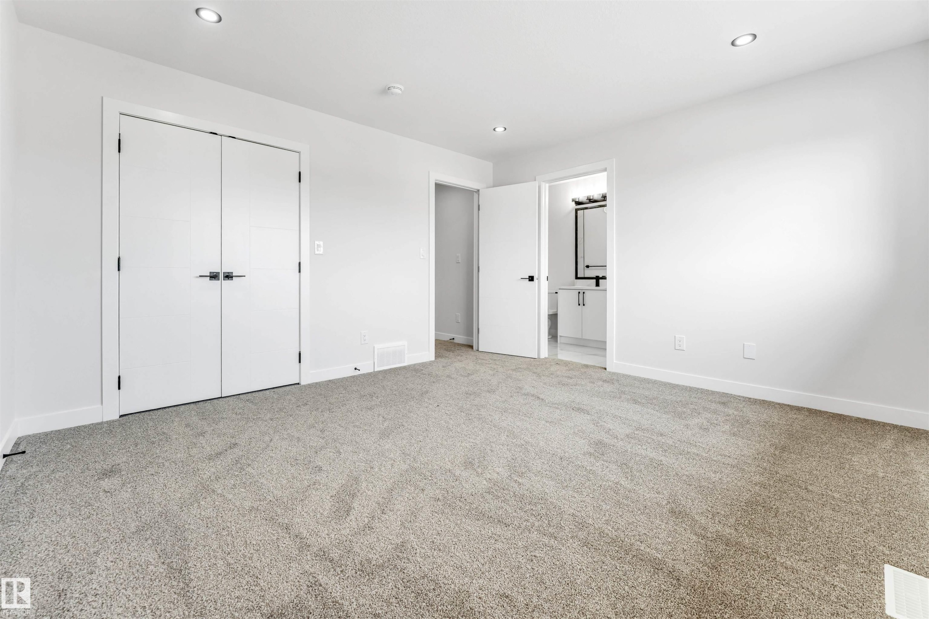 Spacious room featuring neutral carpeting, white walls, recessed lighting, and white bi-fold closet doors with dark hardware - 1714 27 St. Nw, Edmonton, AB - Indoor Photo Showing Other Room