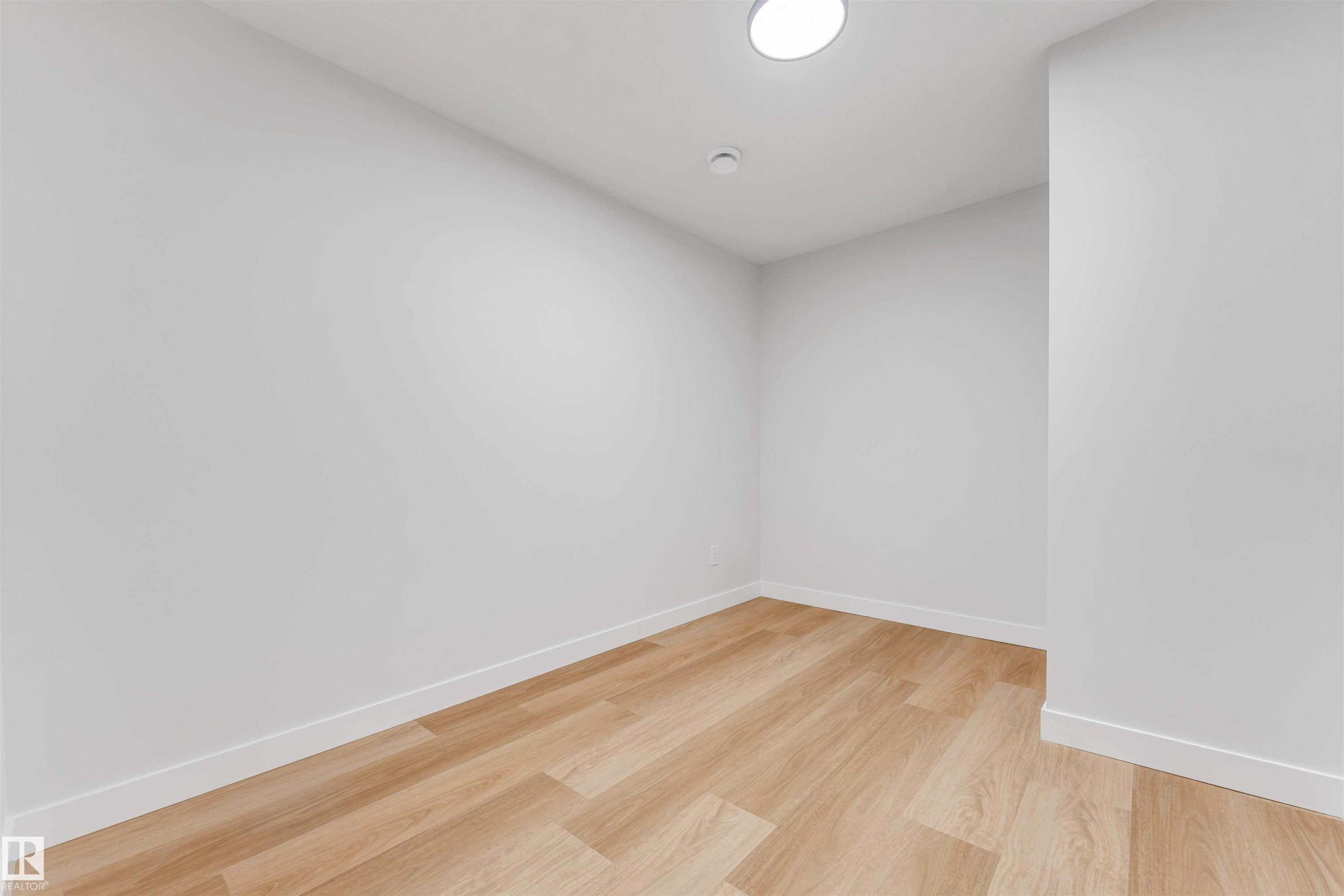 Room featuring light wood-finish flooring, white baseboards, and a circular flush-mount ceiling light - 1714 27 St. Nw, Edmonton, AB - Indoor Photo Showing Other Room