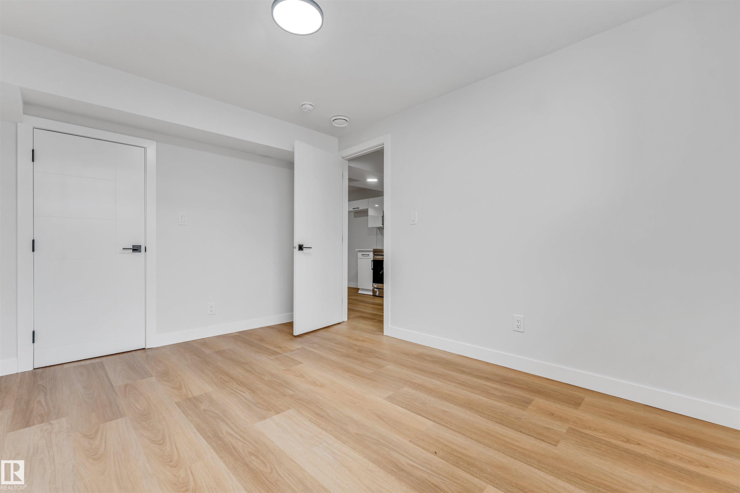 Spacious room featuring light wood-finish flooring, crisp white walls, and a recessed ceiling light - 1714 27 St. Nw, Edmonton, AB - Indoor Photo Showing Other Room