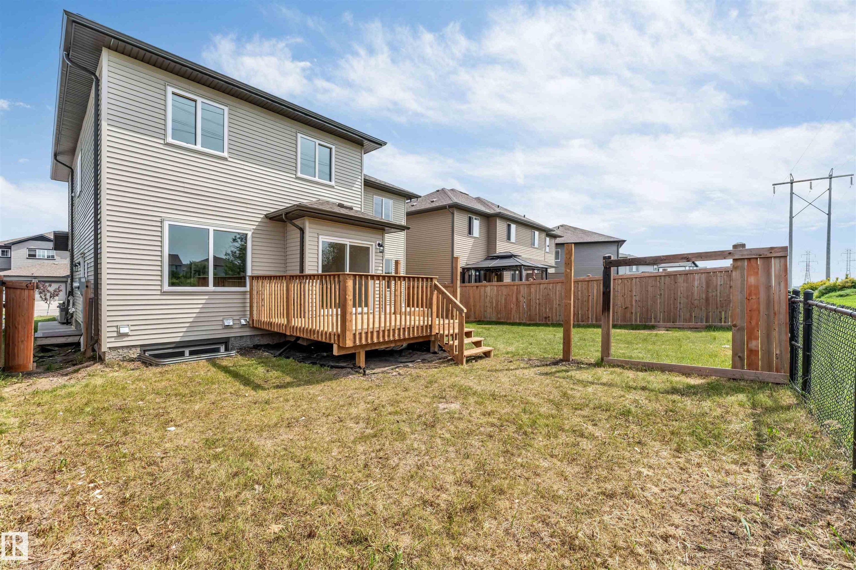 Rear exterior featuring a wooden deck with railing, siding facade, and multiple windows - 1714 27 St. Nw, Edmonton, AB - Outdoor With Exterior