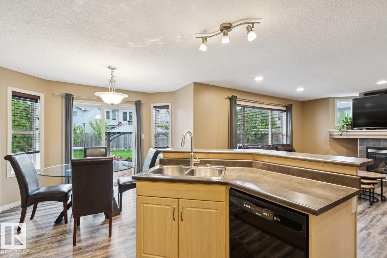 Central kitchen island with an integrated double sink, wood-finish cabinetry, and dark countertops - 16765 119 Street Nw, Edmonton, AB - Indoor