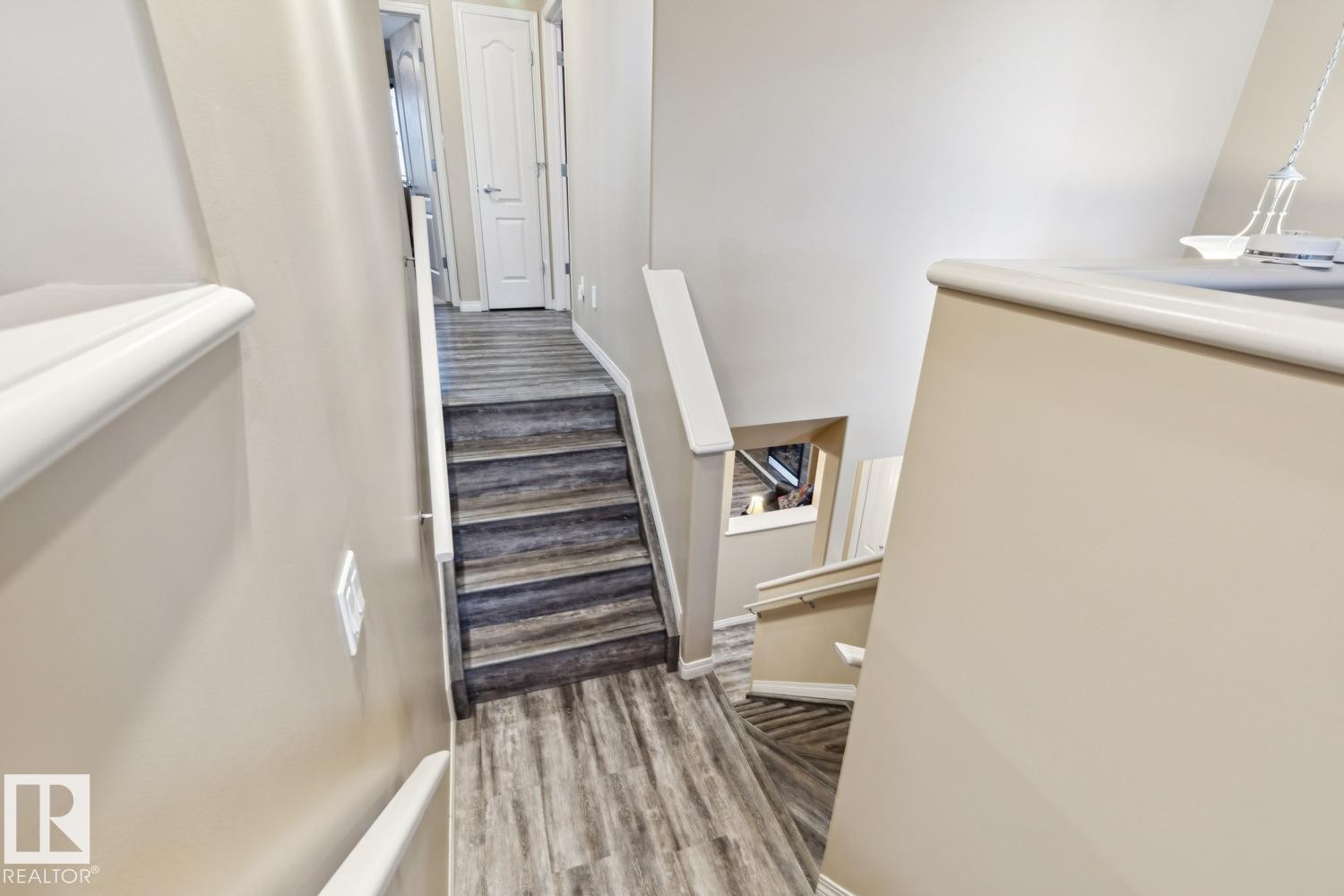 Staircase featuring wood-finish flooring, light tan wall color, white trim, and white handrails - 16765 119 Street Nw, Edmonton, AB - Indoor Photo Showing Other Room
