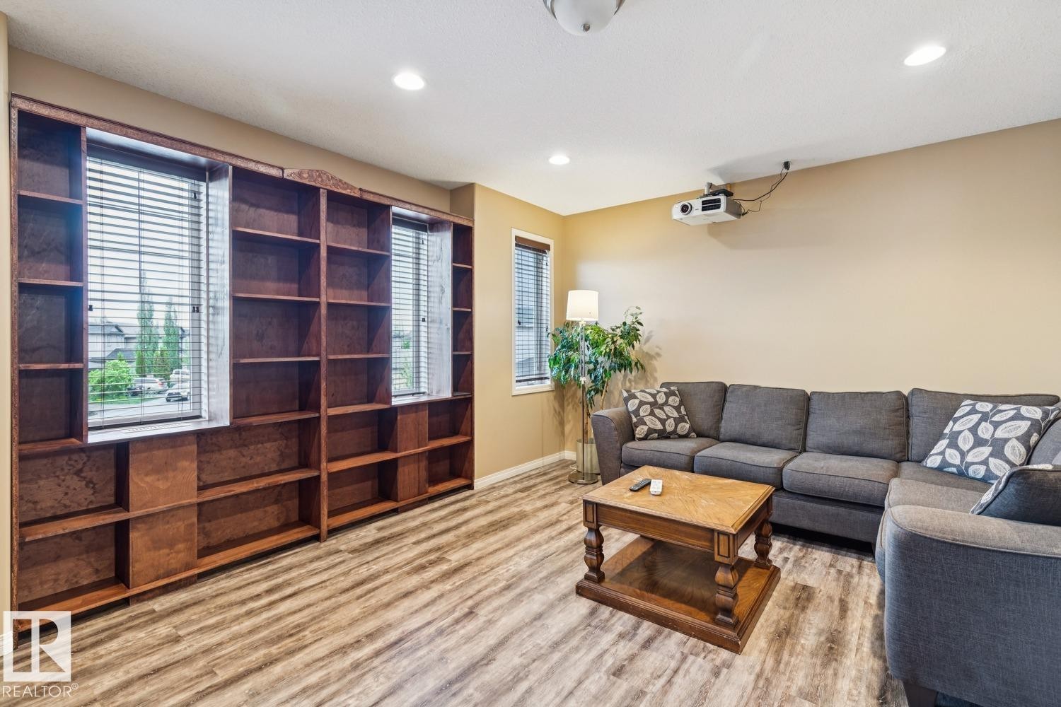 Built-in wood shelving and cabinetry with two windows, recessed lighting, and wood-finish flooring - 16765 119 Street Nw, Edmonton, AB - Indoor Photo Showing Living Room