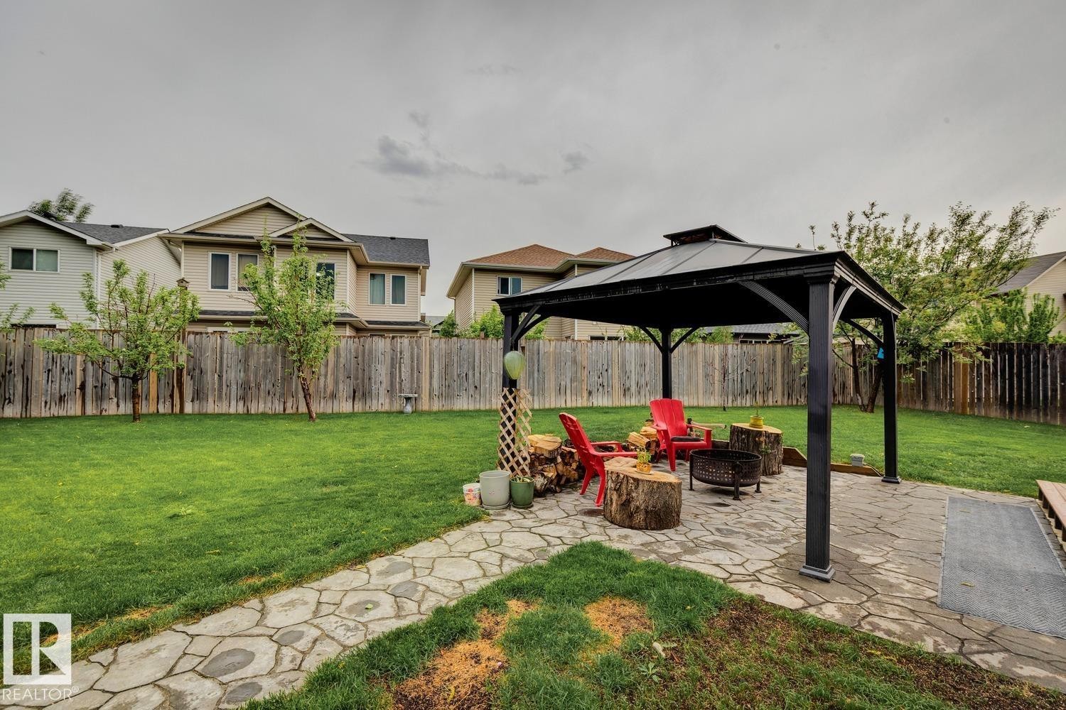 Spacious backyard featuring an expansive lawn, a stone pathway, and a covered gazebo with a flagstone patio - 16765 119 Street Nw, Edmonton, AB - Outdoor With Backyard