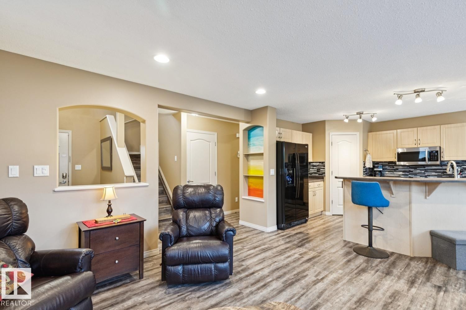 Open-concept living space featuring wood-finish flooring, recessed lighting, and an arched wall opening - 16765 119 Street Nw, Edmonton, AB - Indoor
